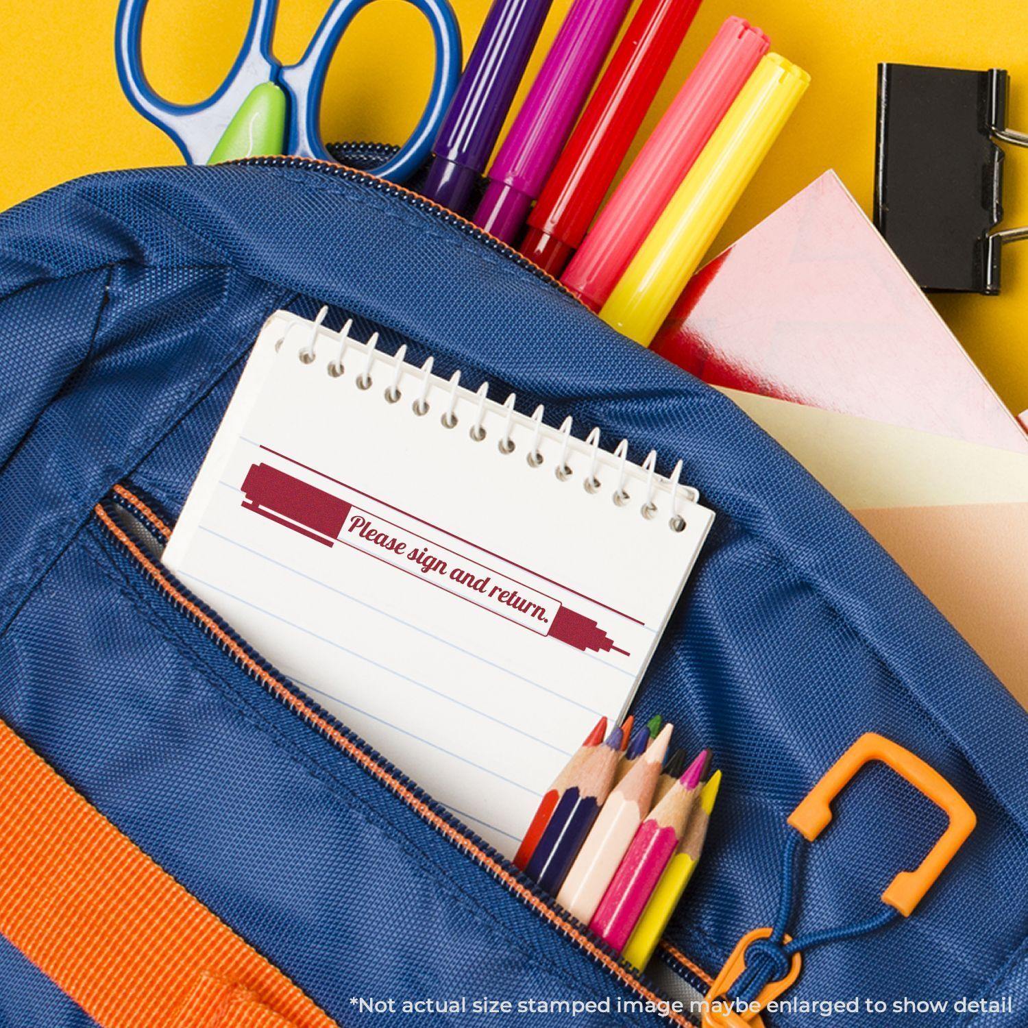 A blue backpack with colored pencils, pens, and a notebook stamped with Please Sign and Return with Pen Rubber Stamp on the page.