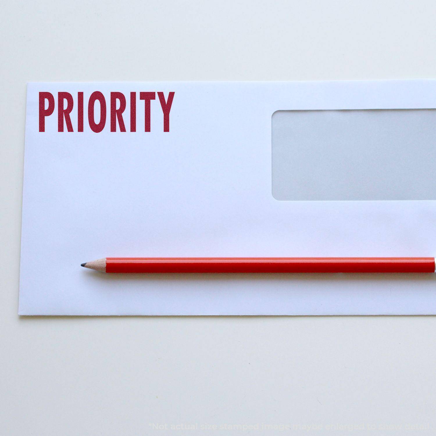 A white envelope stamped with PRIORITY in red using a Large Priority Rubber Stamp, with a red pencil placed on top.