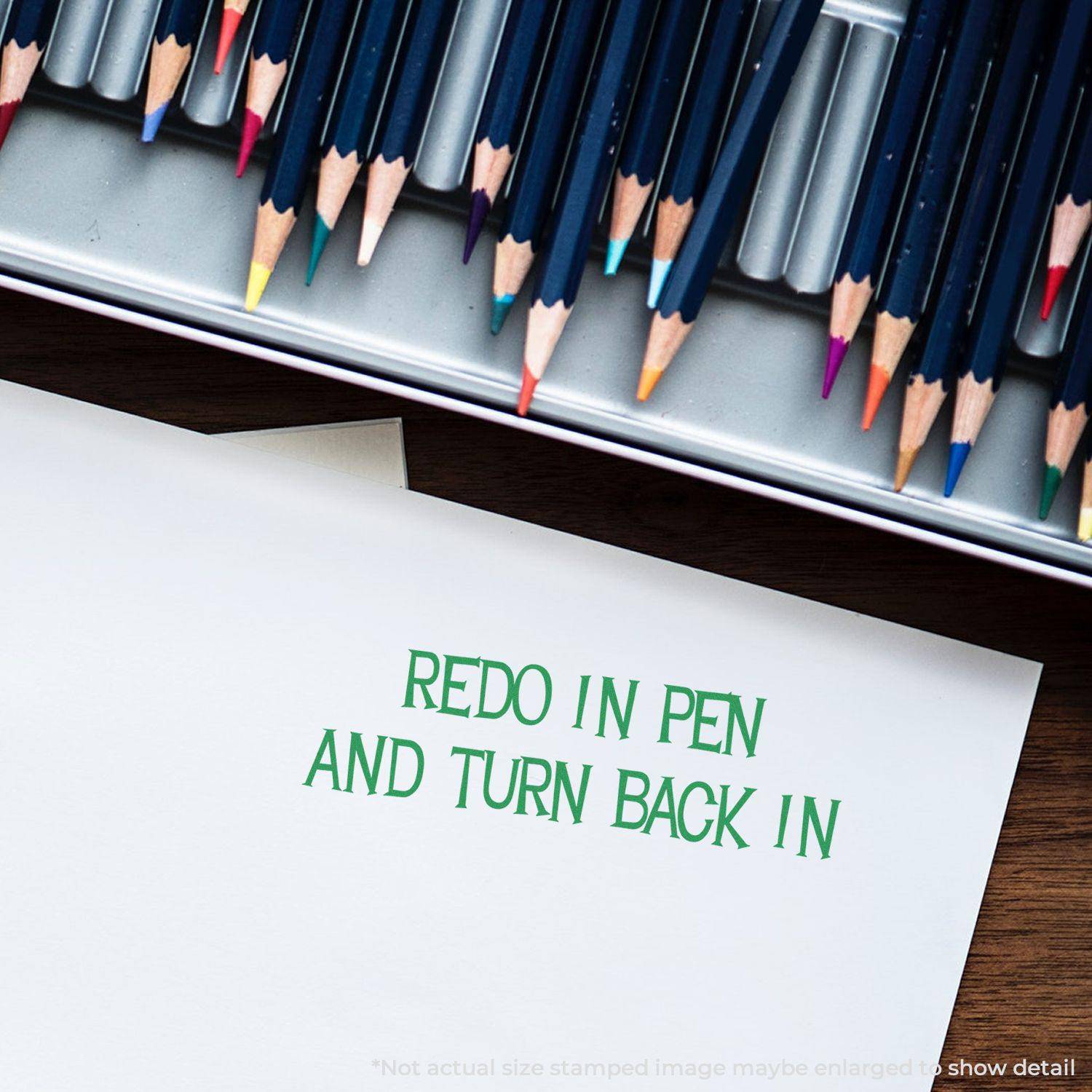 Large Redo In Pen And Turn Back Into Teacher Rubber Stamp impression on paper, surrounded by colored pencils in a metal case.