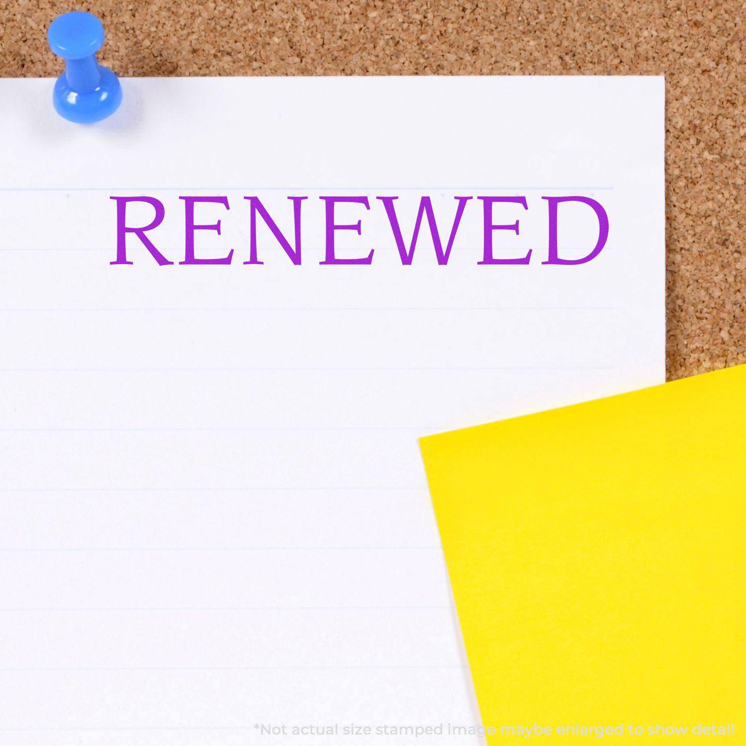A Large Renewed Rubber Stamp imprint in purple ink on a white lined paper pinned to a corkboard, with a yellow paper partially visible.
