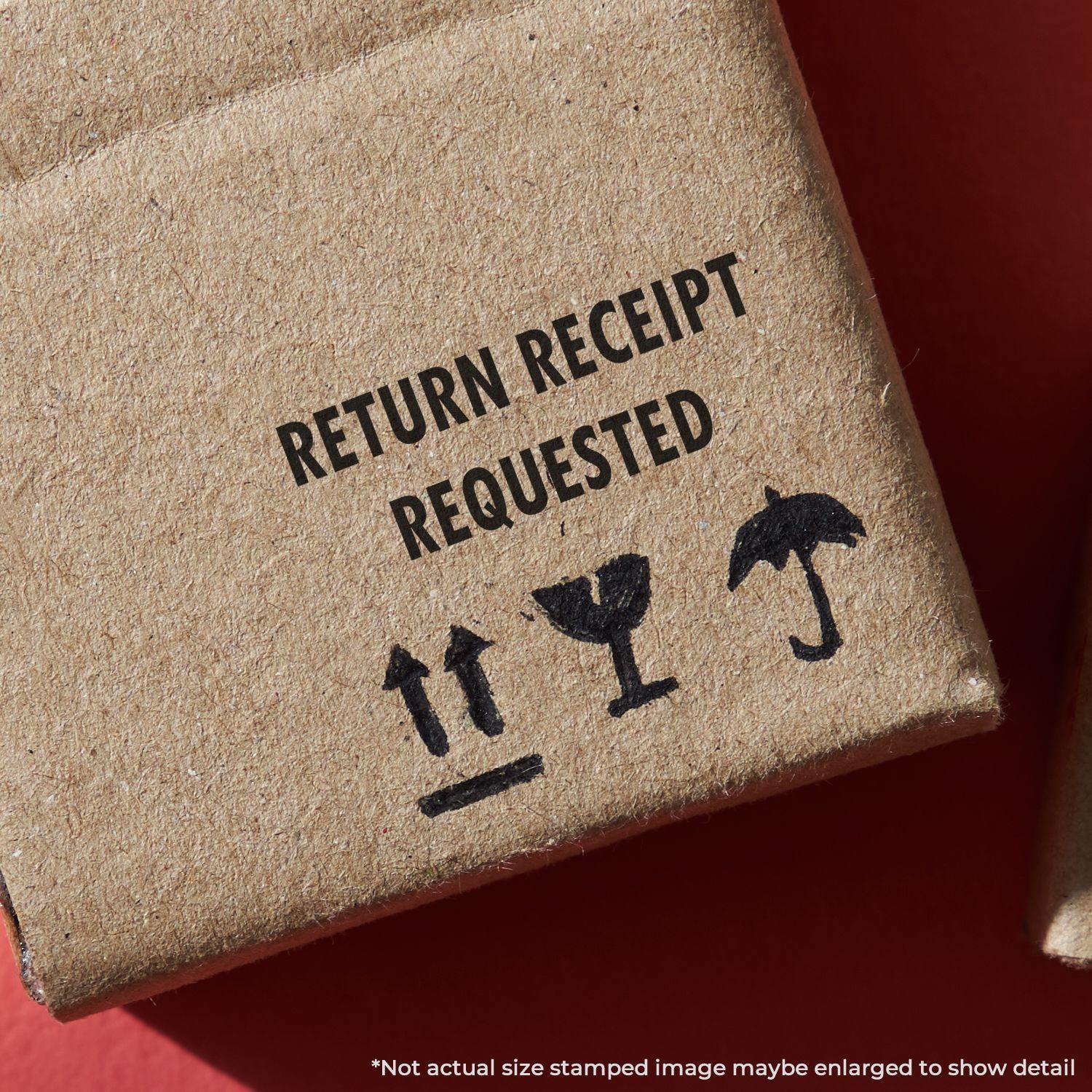Return Receipt Requested rubber stamp on a brown cardboard box with icons for fragile, this side up, and keep dry.
