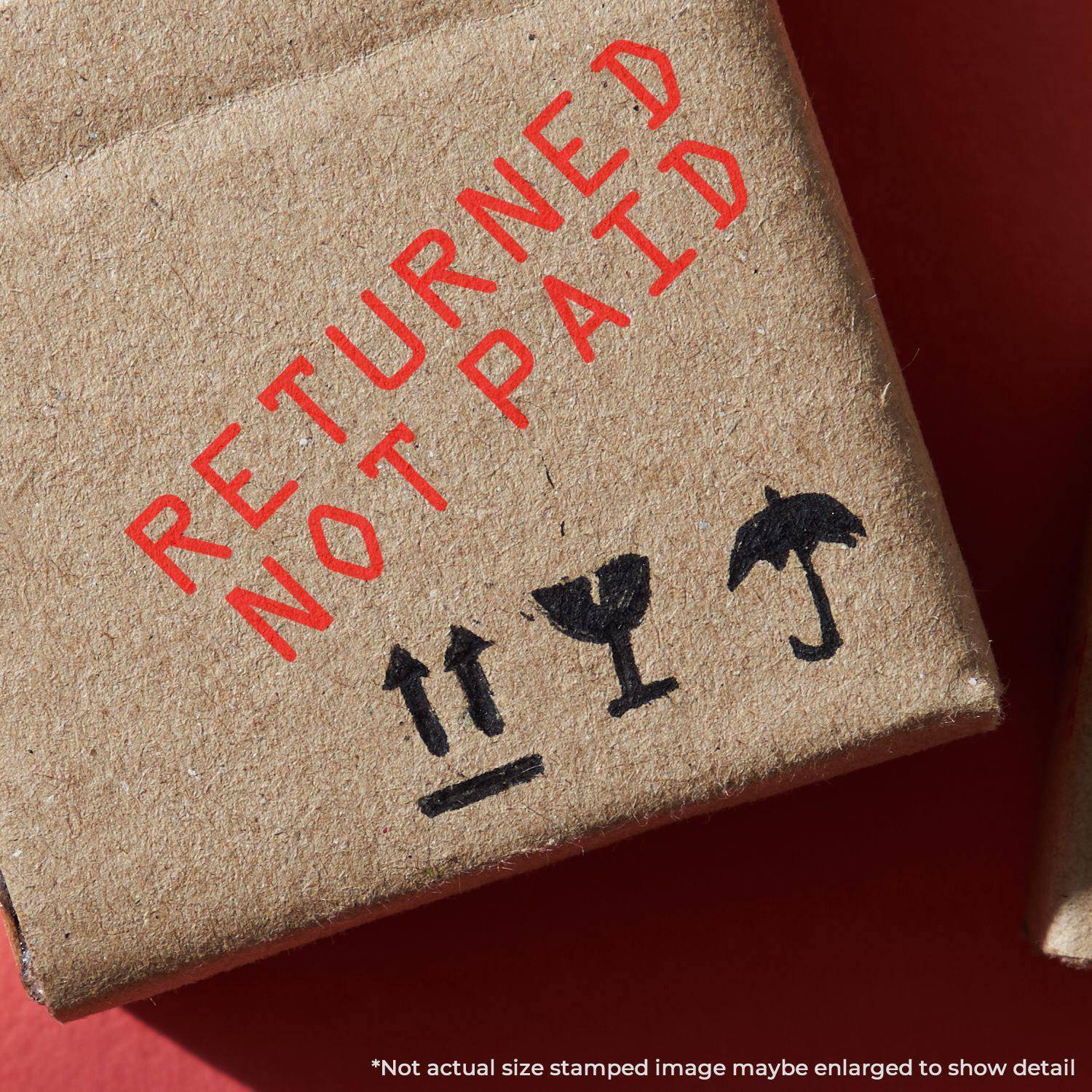 Close-up of a cardboard box stamped with RETURNED NOT PAID in red ink using the Large Pre-Inked Returned Not Paid Stamp.