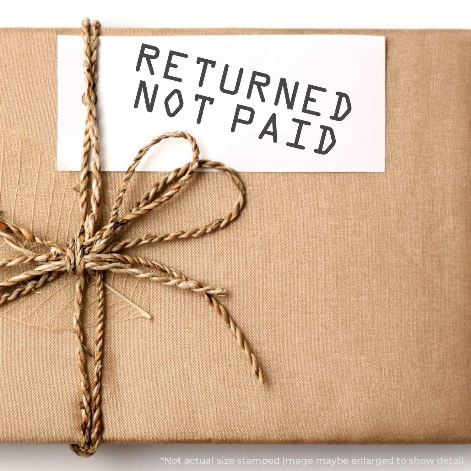 A Large Returned Not Paid Rubber Stamp is used on a white card attached to a brown wrapped package with twine.