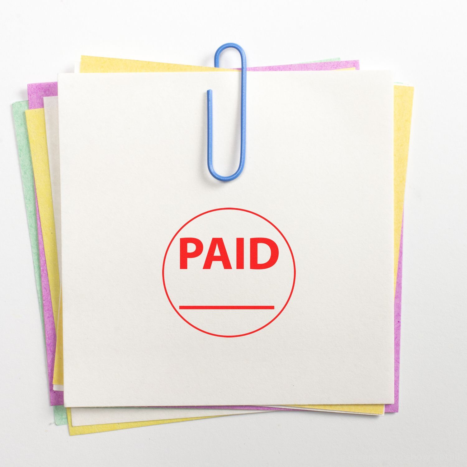 Self Inking Round Paid with Line Stamp in red ink on white paper, clipped with a blue paperclip to colored sheets.