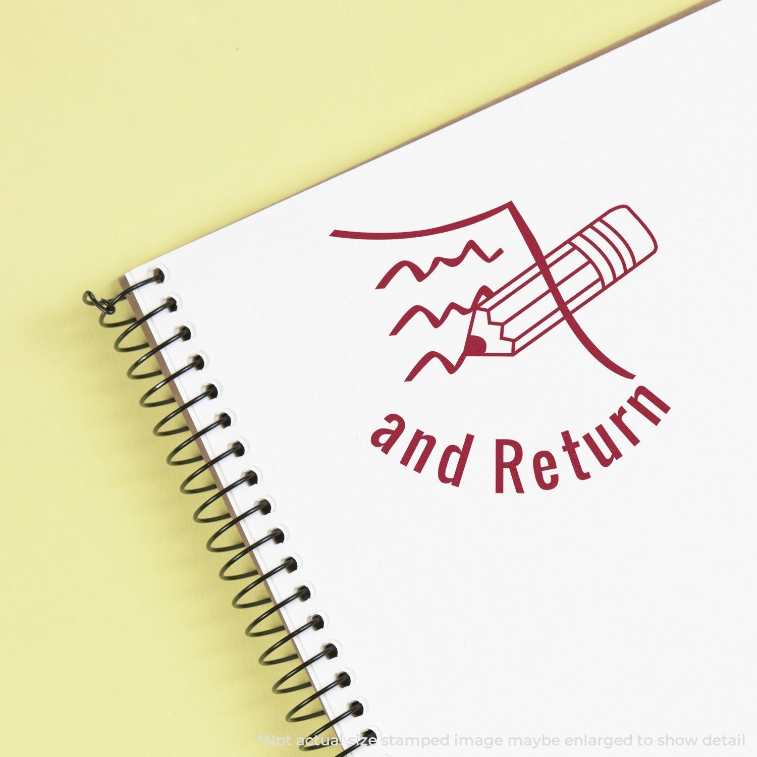 Self Inking Round Sign and Return Stamp used on a spiral notebook, showing a red stamped image of a pencil and the words and Return.
