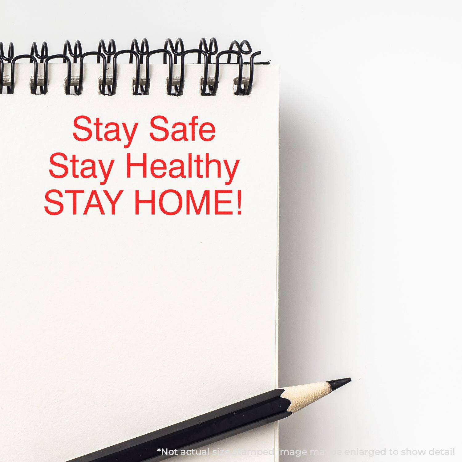 A notebook with Stay Safe Stay Healthy STAY HOME! stamped in red using the Large Pre-Inked Stay Safe Stay Healthy Stamp, next to a pencil.