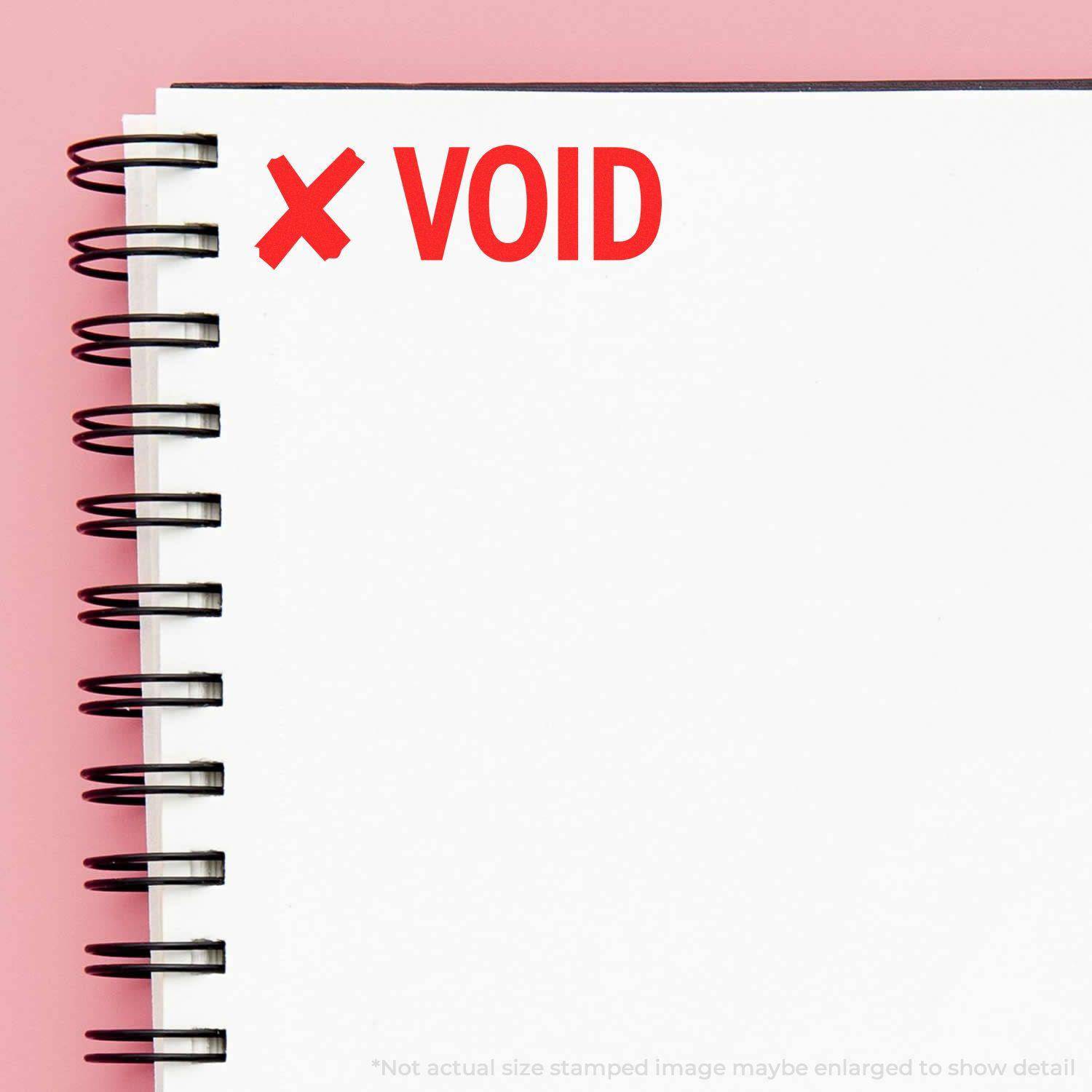 Large Pre-Inked Void with X Stamp used on a white spiral notebook, showing a red X and VOID text on a pink background.