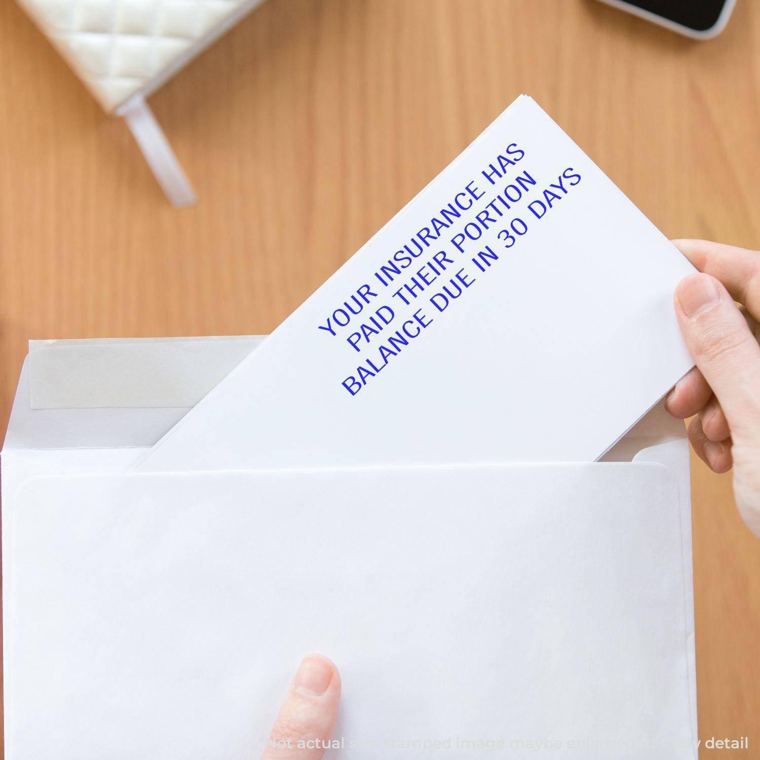 Person holding an envelope stamped with YOUR INSURANCE HAS PAID THEIR PORTION using the Large Pre-Inked Your Insurance Has Paid Their Portion Stamp.