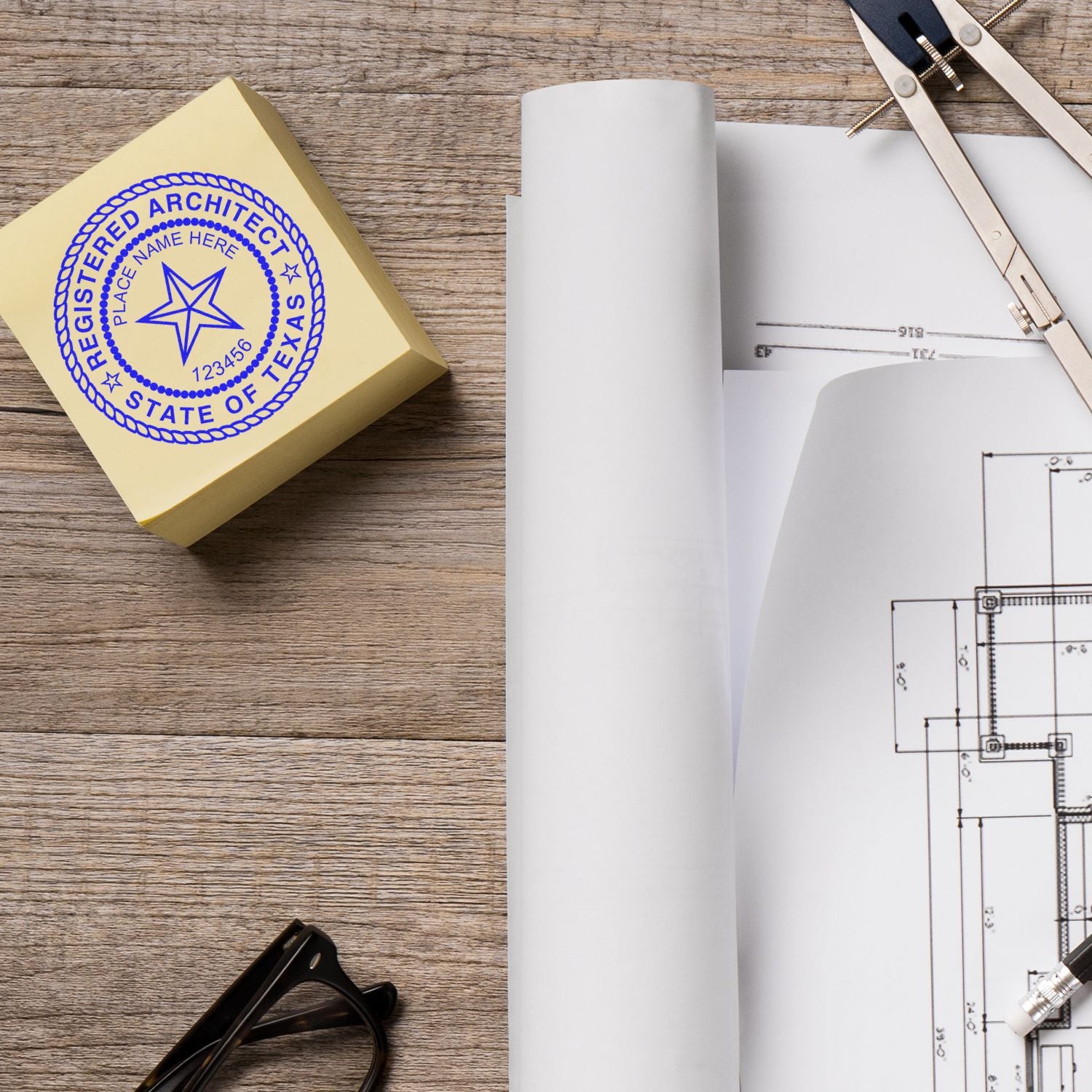 Self Inking Texas Architect Stamp on a desk with architectural plans, compass, and glasses.