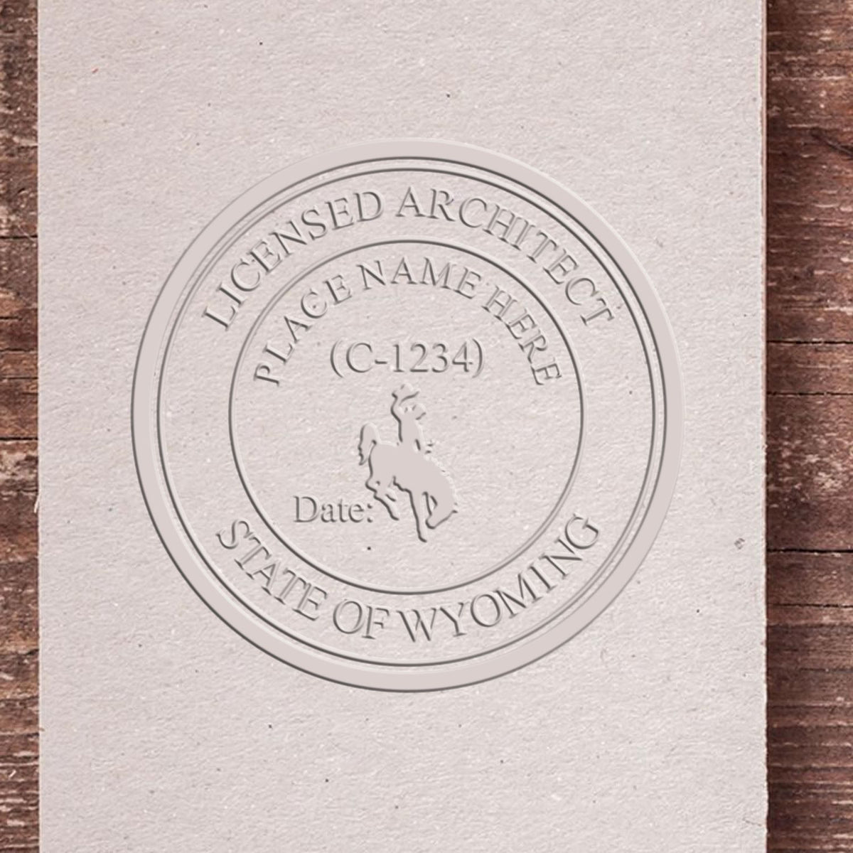 A lifestyle photo showing a stamped image of the Handheld Wyoming Architect Seal Embosser on a piece of paper