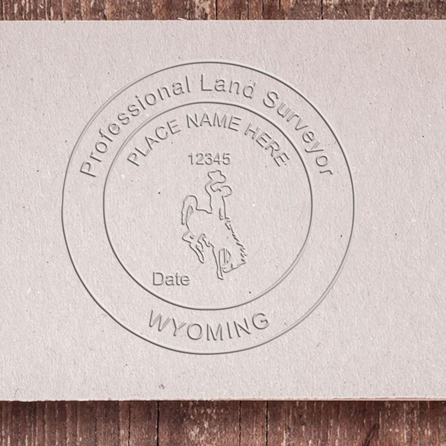 A lifestyle photo showing a stamped image of the Handheld Wyoming Land Surveyor Seal on a piece of paper