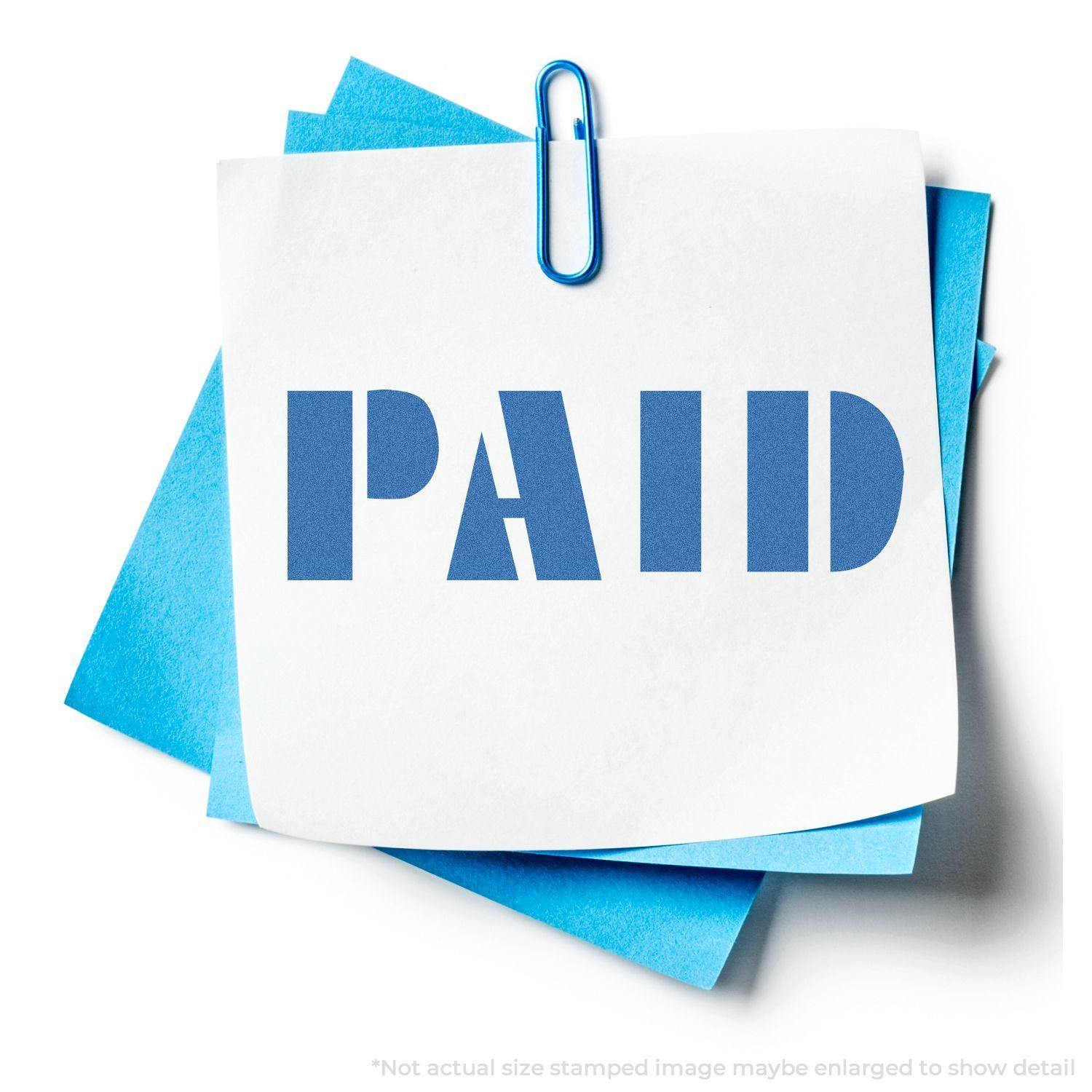 A Blue Paid Xstamper Stamp imprint on a white paper clipped to blue sheets, showing the word PAID in bold blue letters.