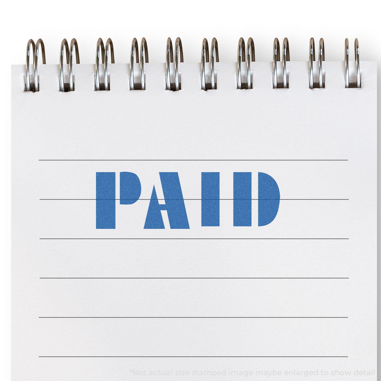 Blue Paid Xstamper Stamp imprint on a white spiral notebook with lined paper.