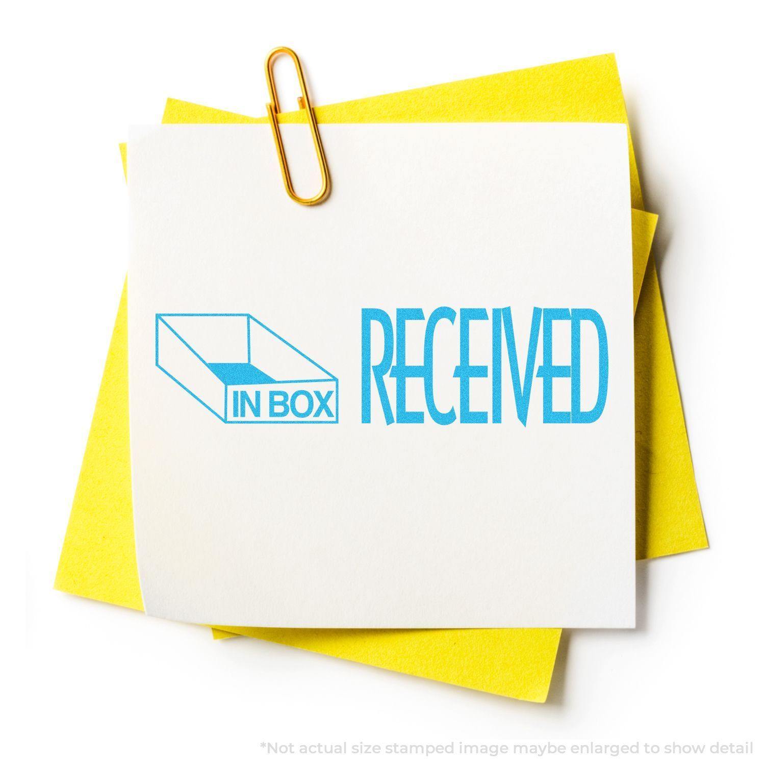 Blue Received Xstamper Stamp marking IN BOX RECEIVED on a white paper clipped to yellow sheets.