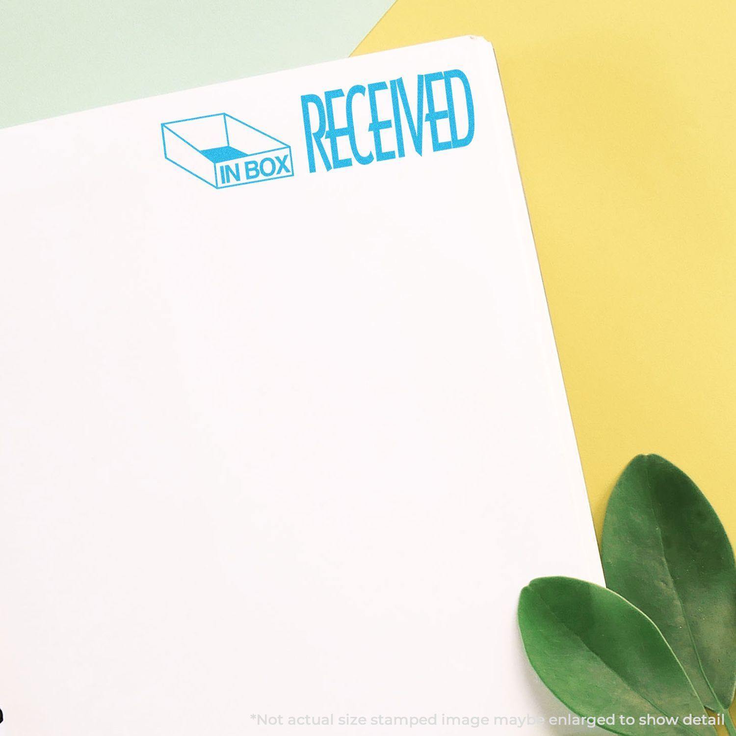 Blue Received Xstamper Stamp marking RECEIVED on a white paper with green leaves in the corner.