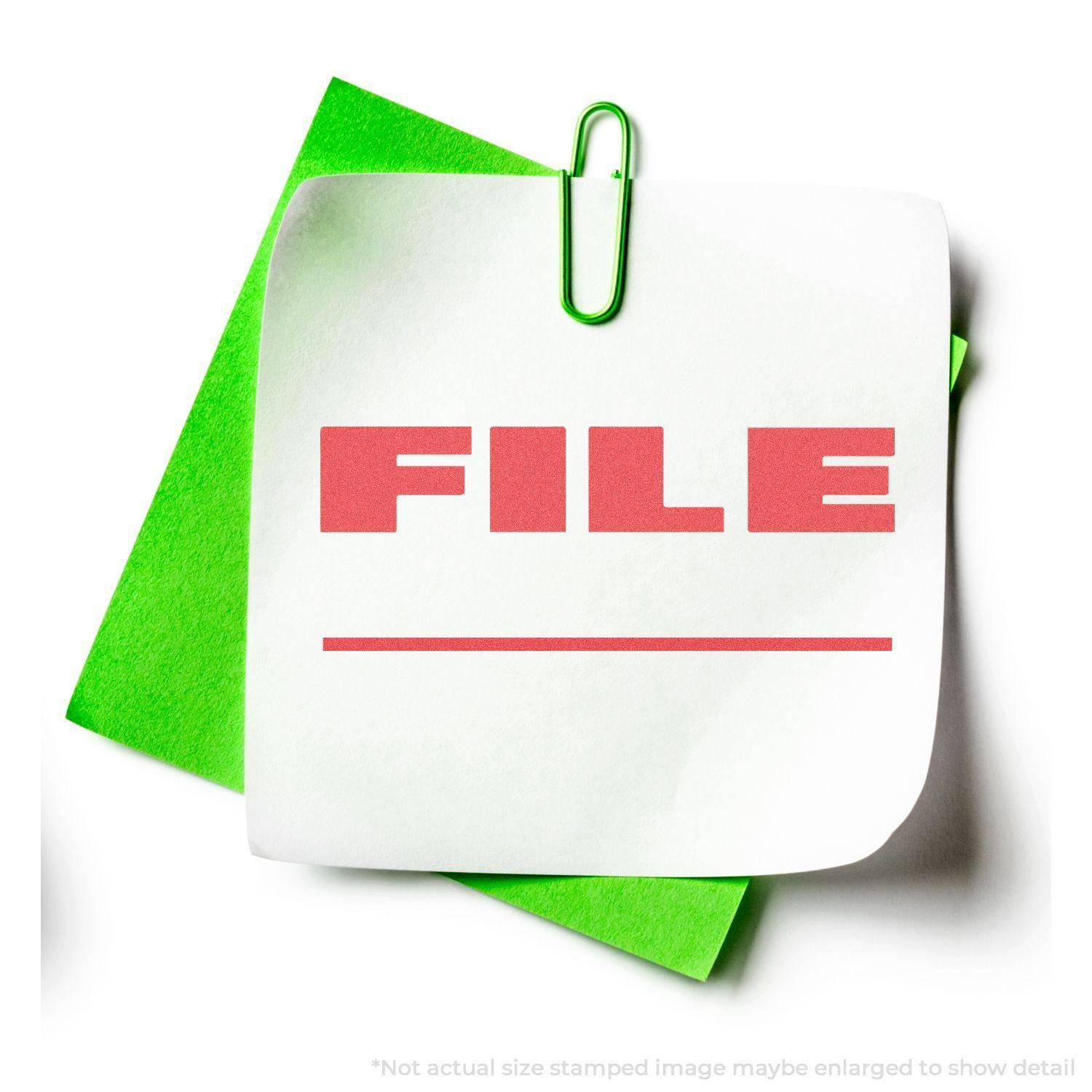 Bold Red File Xstamper Stamp imprint on a white paper clipped to a green folder, showcasing the word FILE in bold red letters.