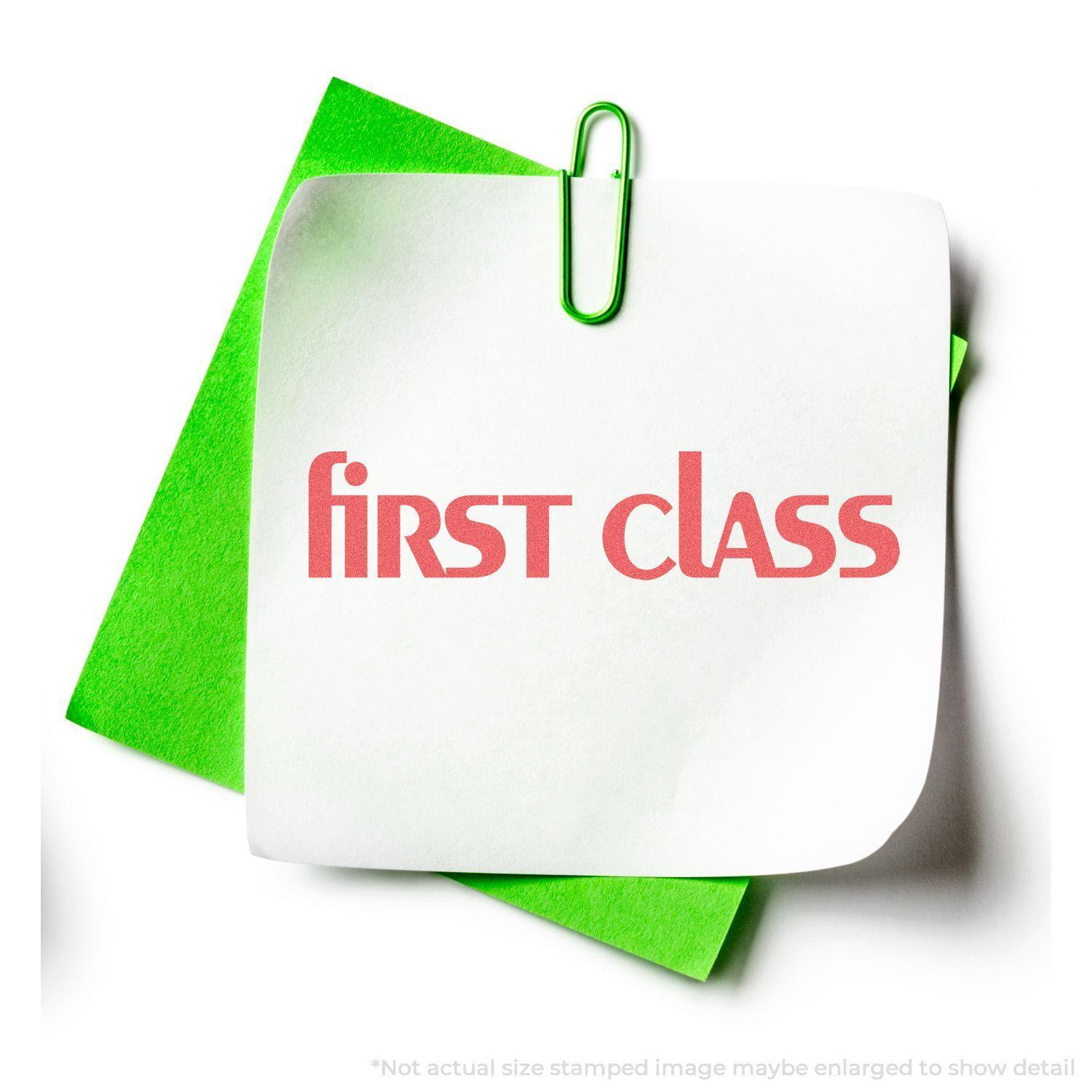 Bold Red First Class Xstamper Stamp impression on white paper, clipped to green paper with a green paperclip.