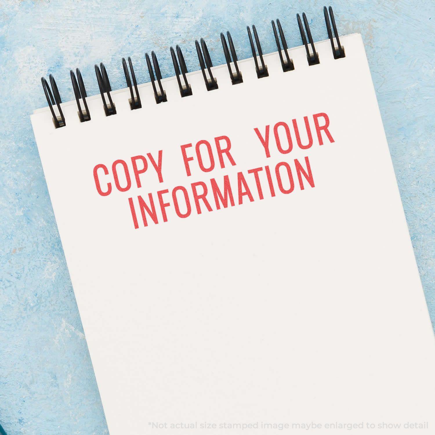 Copy For Your Information Xstamper Stamp used on a white notepad with a blue background. Text is stamped in red ink.