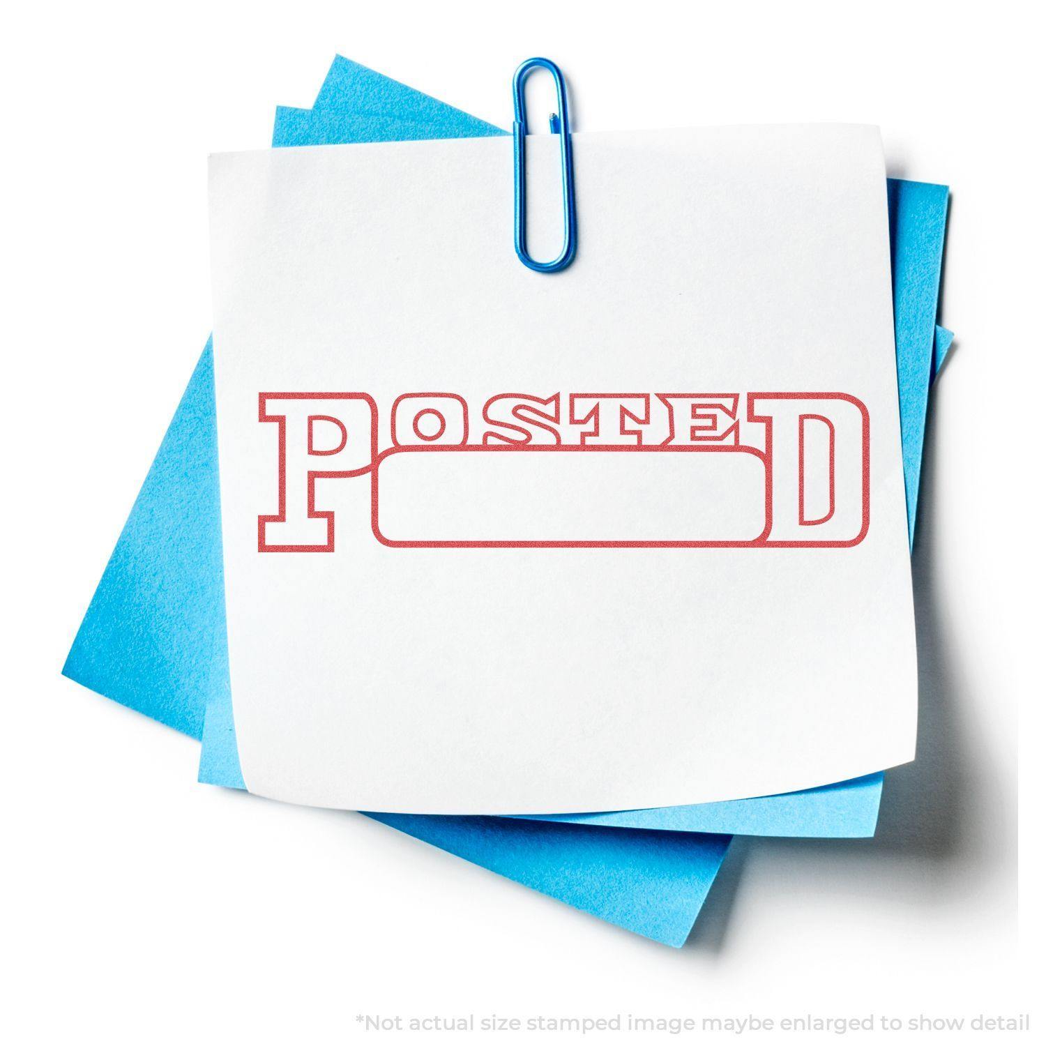 A Date Posted Xstamper Stamp imprint on white paper with a blue paperclip and blue papers in the background.