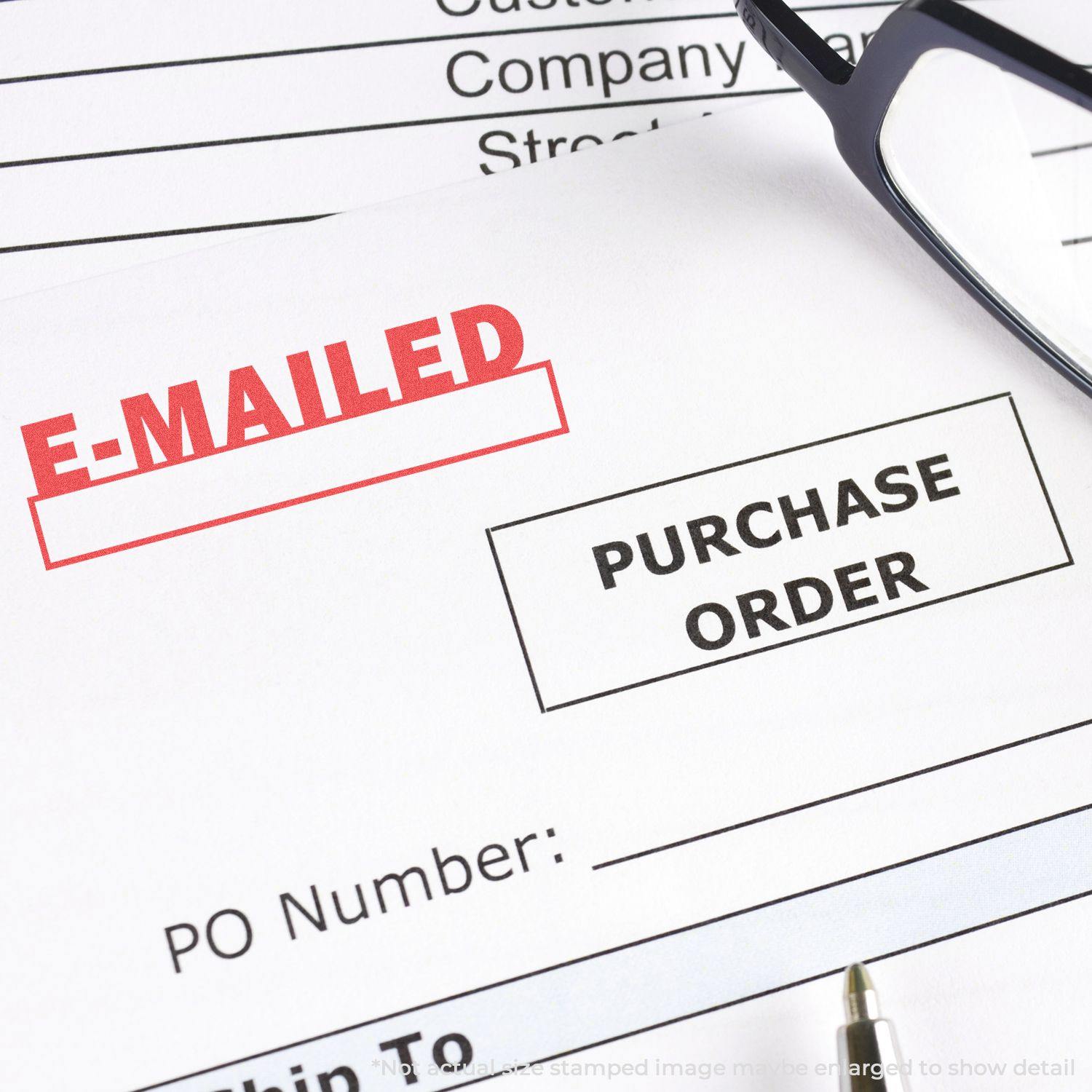 Close-up of a purchase order stamped with the E-Mailed Xstamper Stamp in red ink, with glasses and a pen nearby.