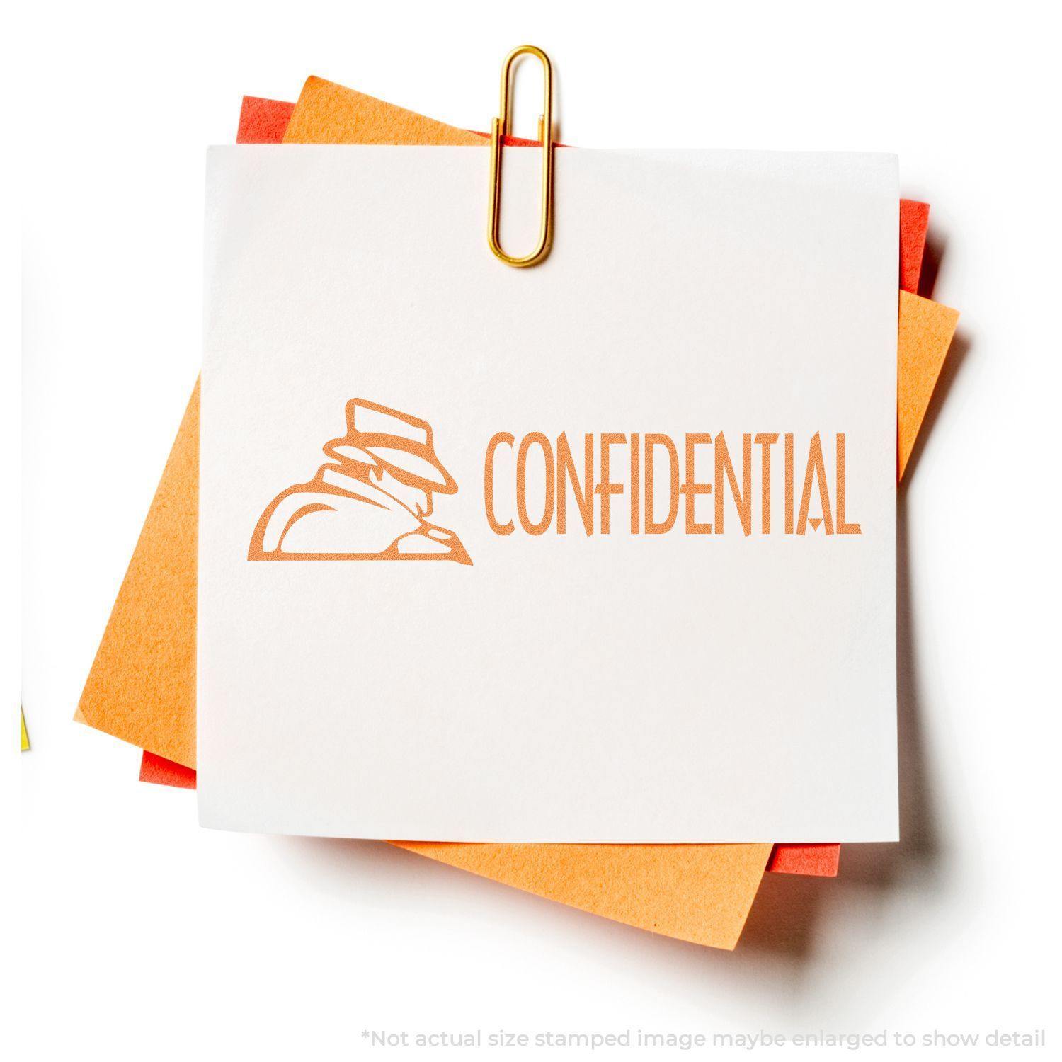 Figure Confidential Xstamper Stamp imprint on white paper with orange and red sheets underneath, held by a gold paperclip.