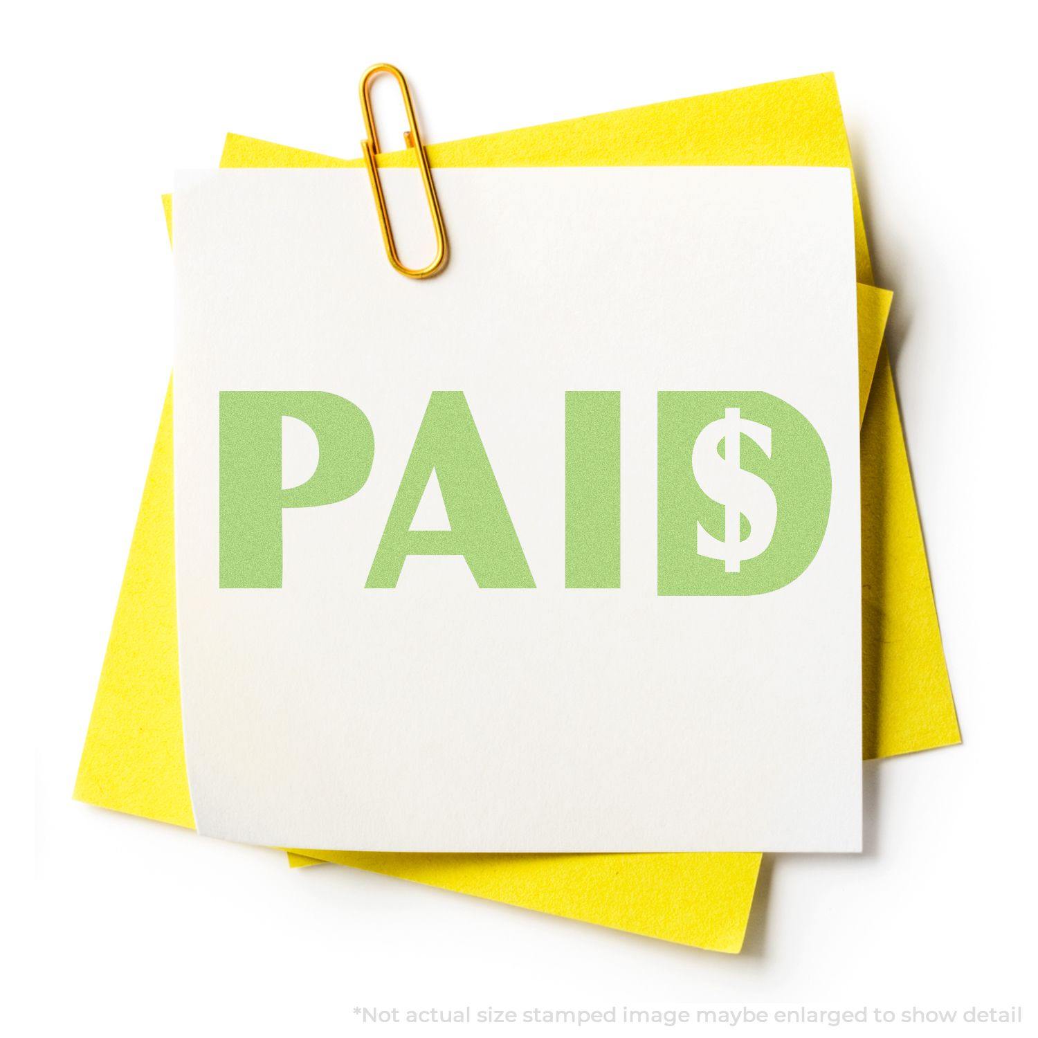 Green Paid Xstamper Stamp imprint on white paper with yellow sticky notes and a paperclip. Text reads PAID in green with a dollar sign.