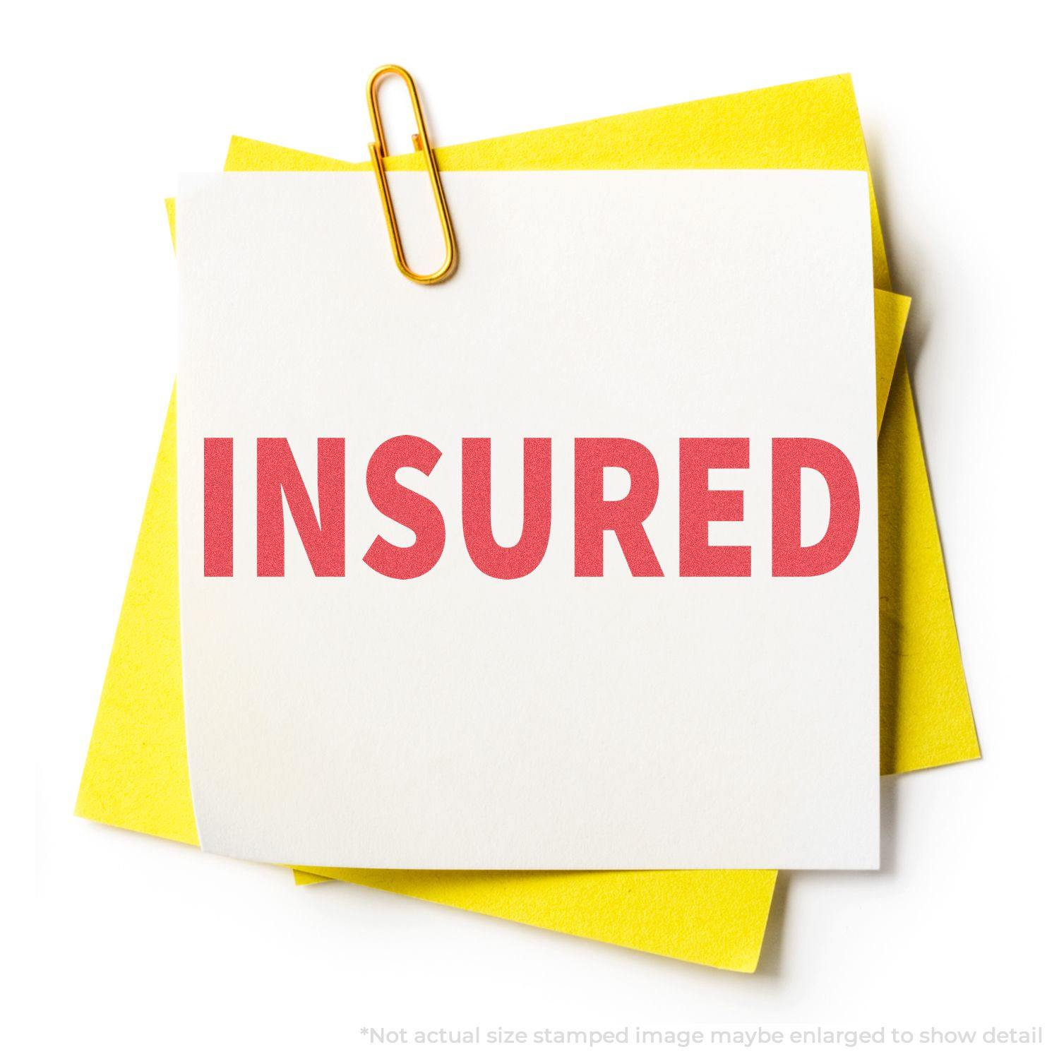 Insured Xstamper Stamp imprint on a white note with a yellow background, held by a paperclip, displaying the word INSURED in red.