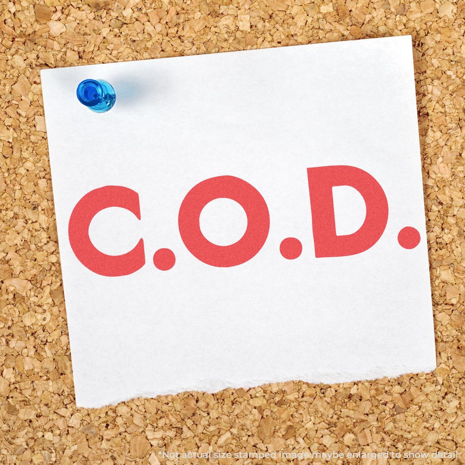 A white note pinned to a corkboard with C.O.D. stamped in bold red using the Jumbo Bold Red C.O.D. Xstamper Stamp.