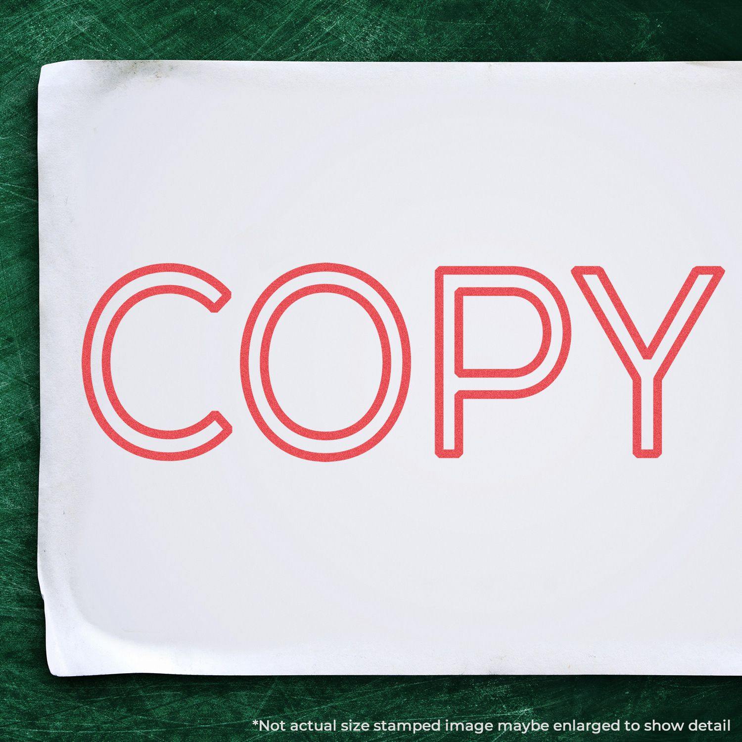 Jumbo Red Copy Xstamper Stamp imprinting the word COPY in bold red letters on a white sheet, placed on a green surface.
