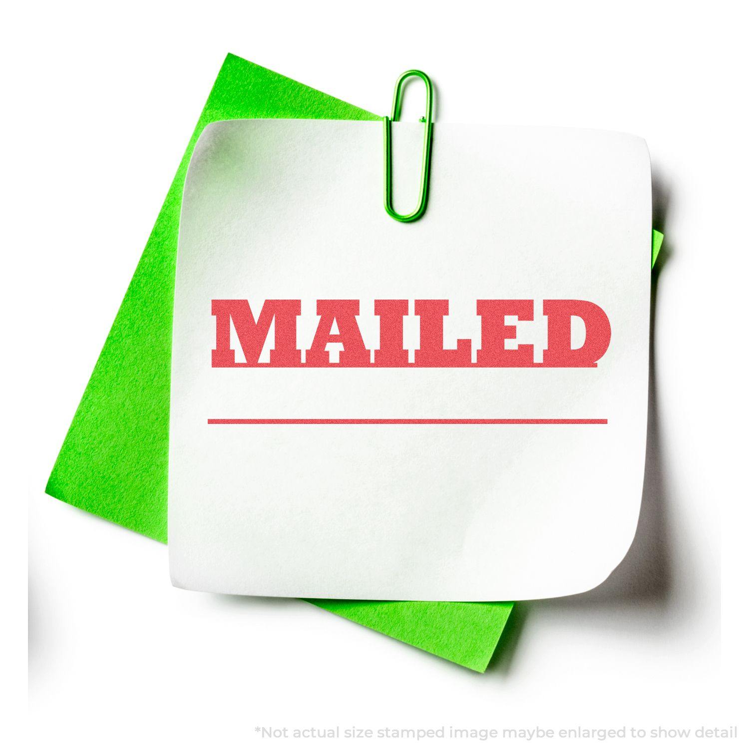 Green paper with a white note stamped MAILED in red using the Mailed Xstamper Stamp, held by a green paperclip.