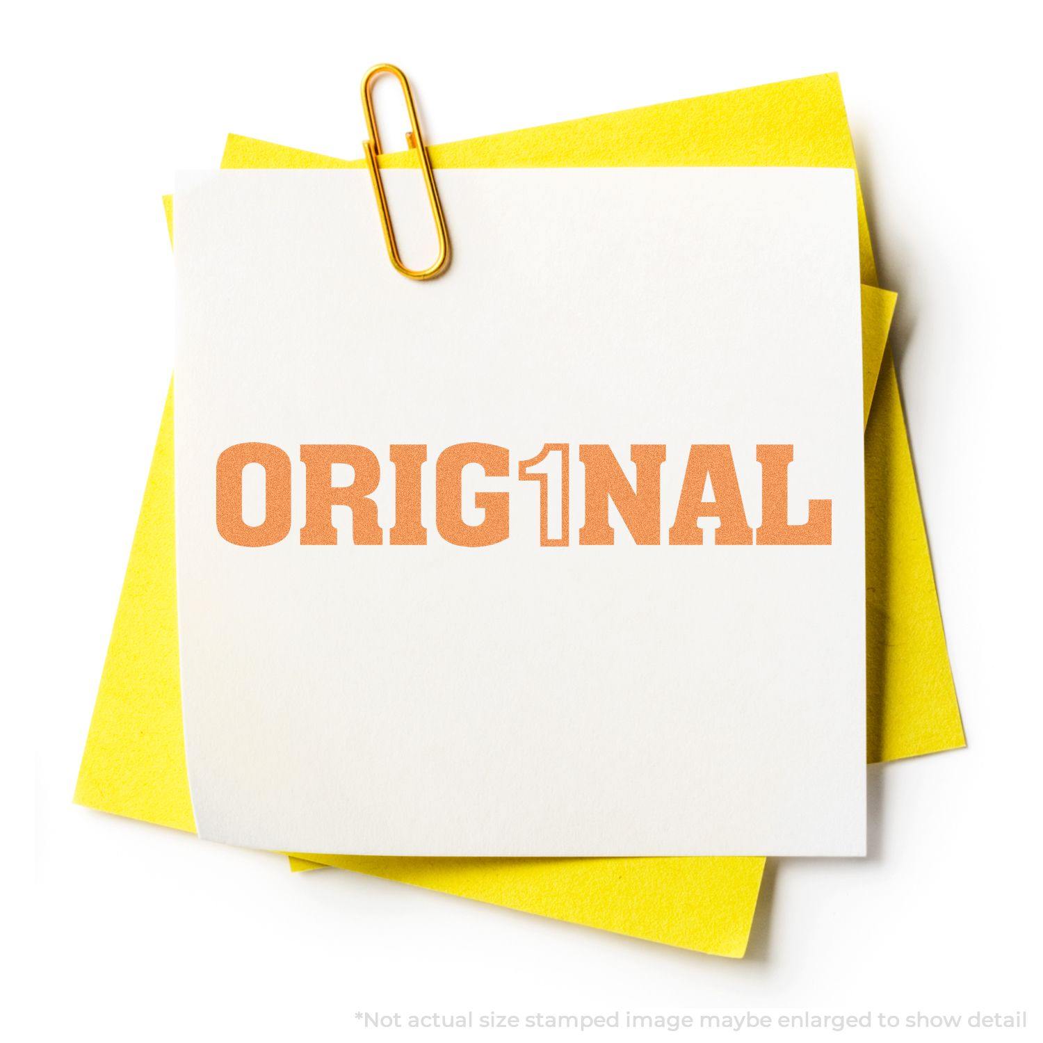 Orig1Nal Xstamper Stamp in use, showing a stamped ORIG1NAL on white paper clipped to yellow paper.