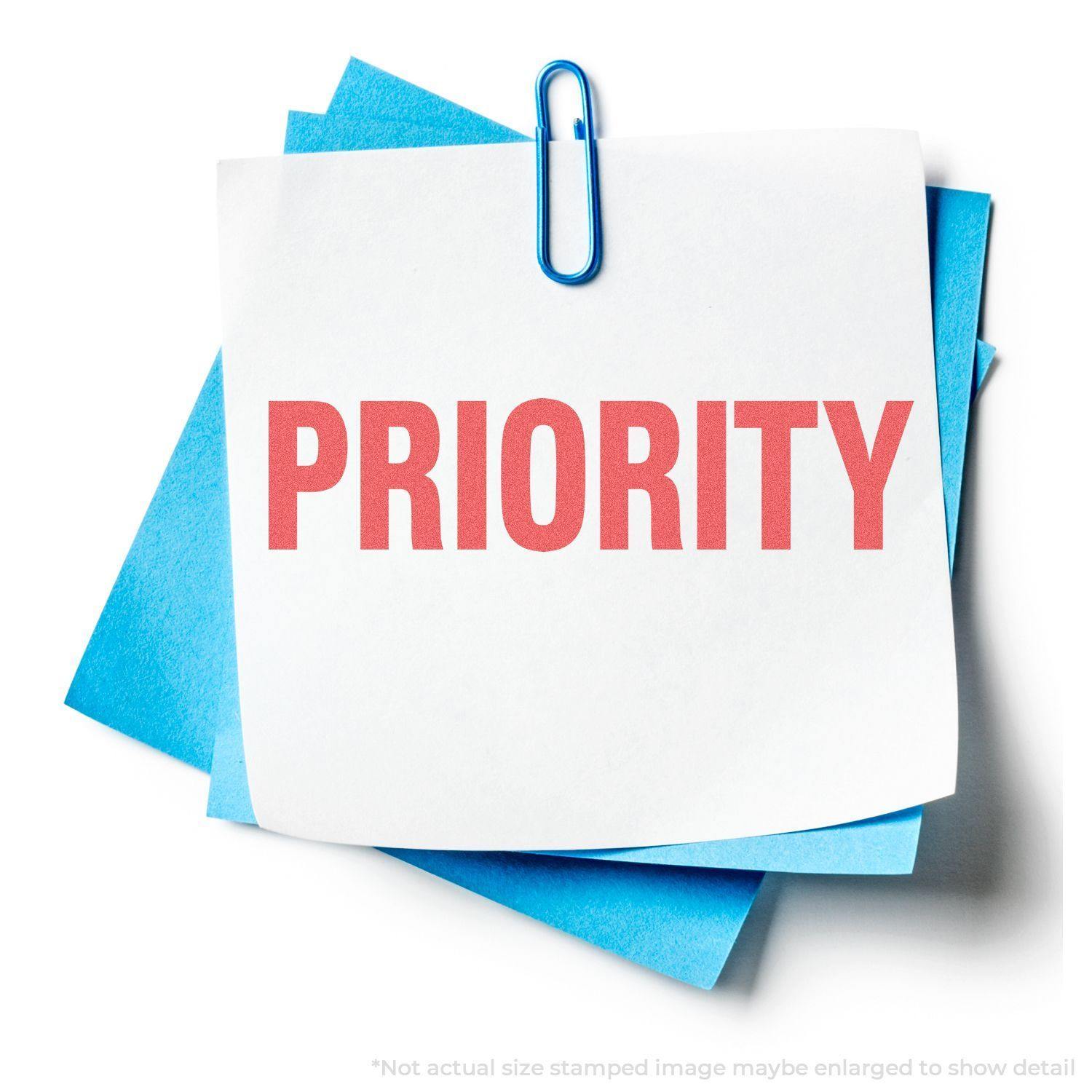 A white paper stamped with PRIORITY in red ink using the Priority Xstamper Stamp, clipped to blue papers with a blue paperclip.