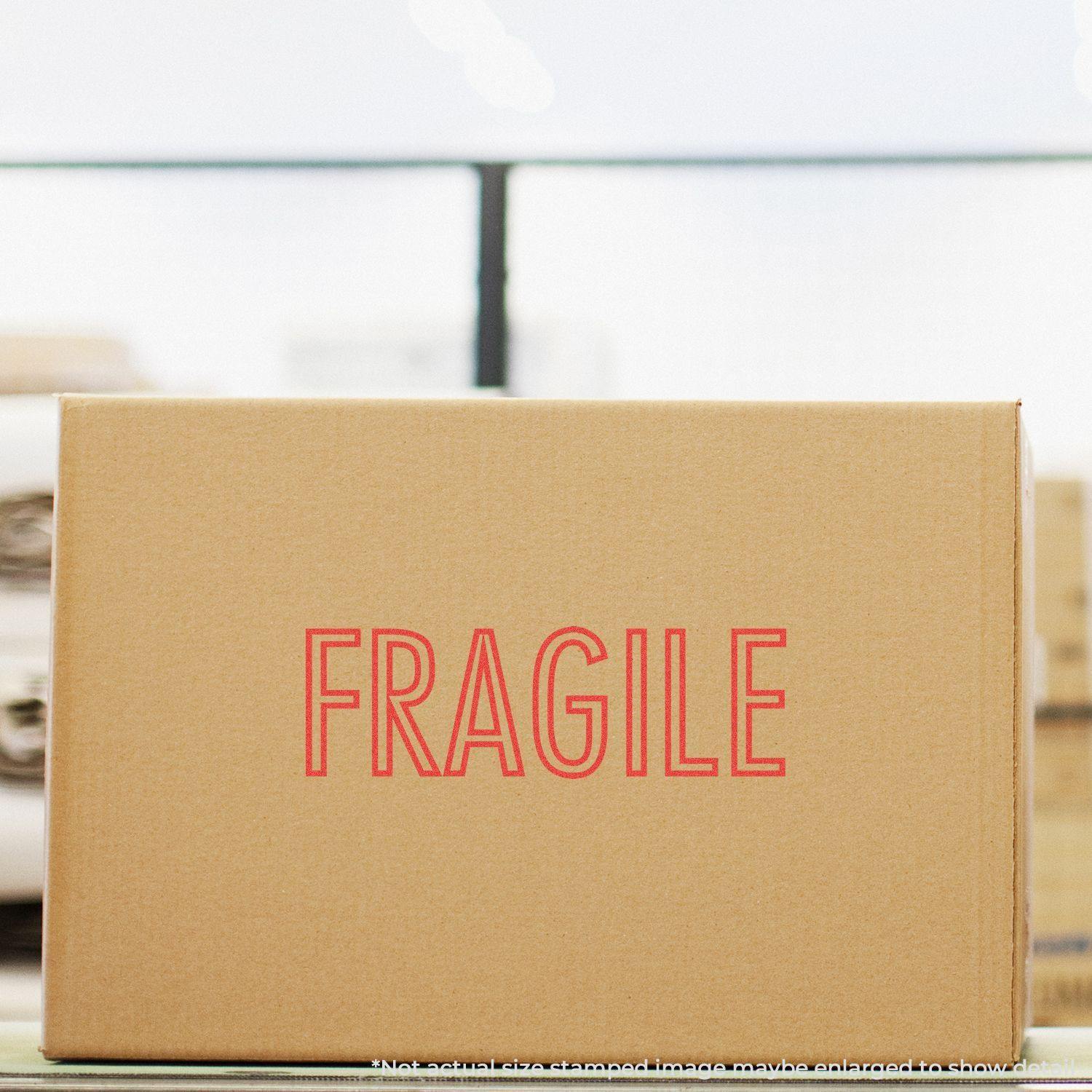 Cardboard box stamped with FRAGILE in red using the Red Fragile Xstamper Stamp, placed in a warehouse setting.