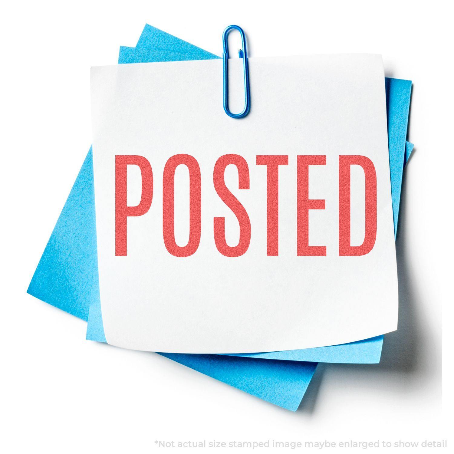 Red Posted Xstamper Stamp imprint on white paper clipped to blue sheets, showcasing the clear and bold POSTED text in red ink.