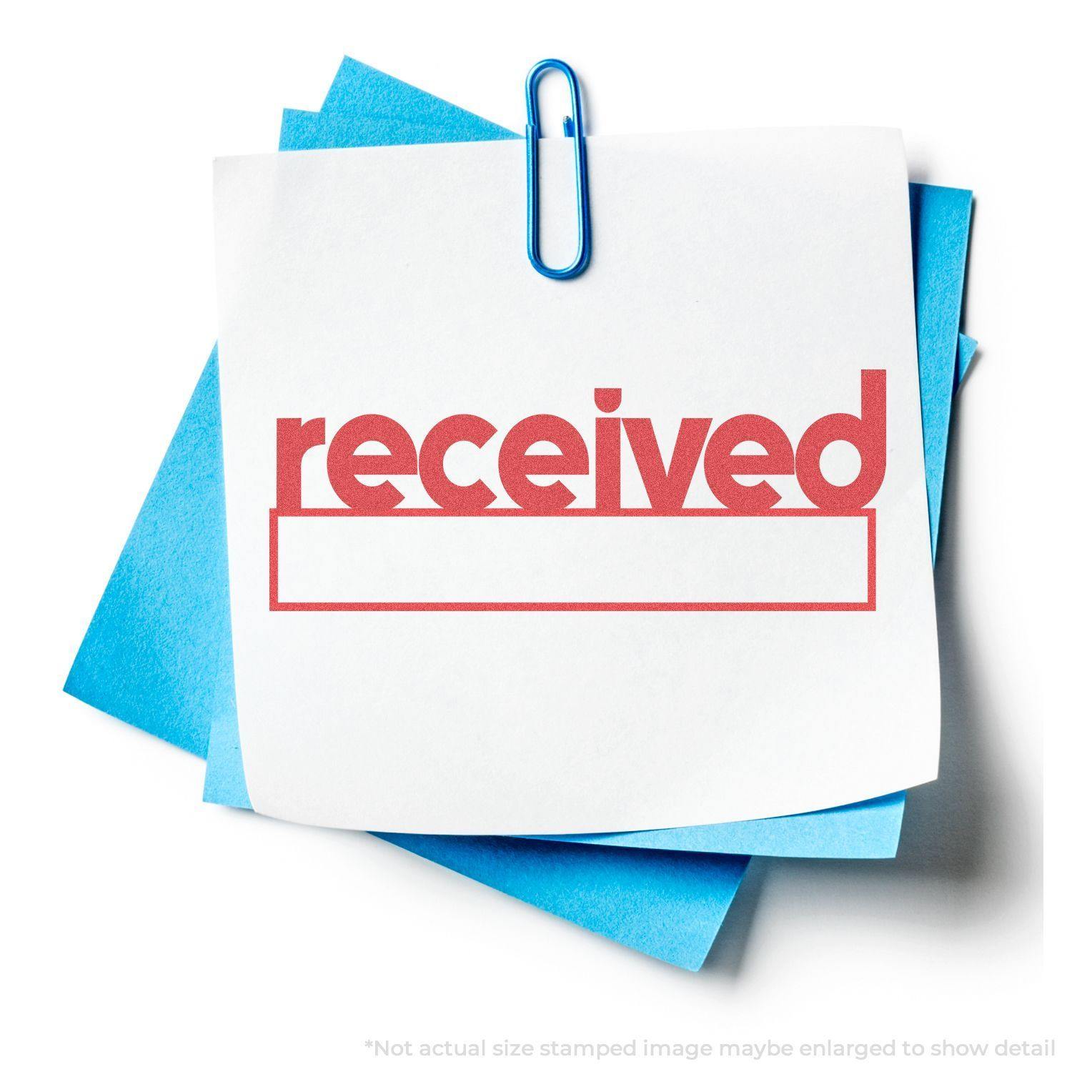 Red Received Xstamper Stamp imprint on a white paper clipped to blue papers, showing the word received in bold red letters.