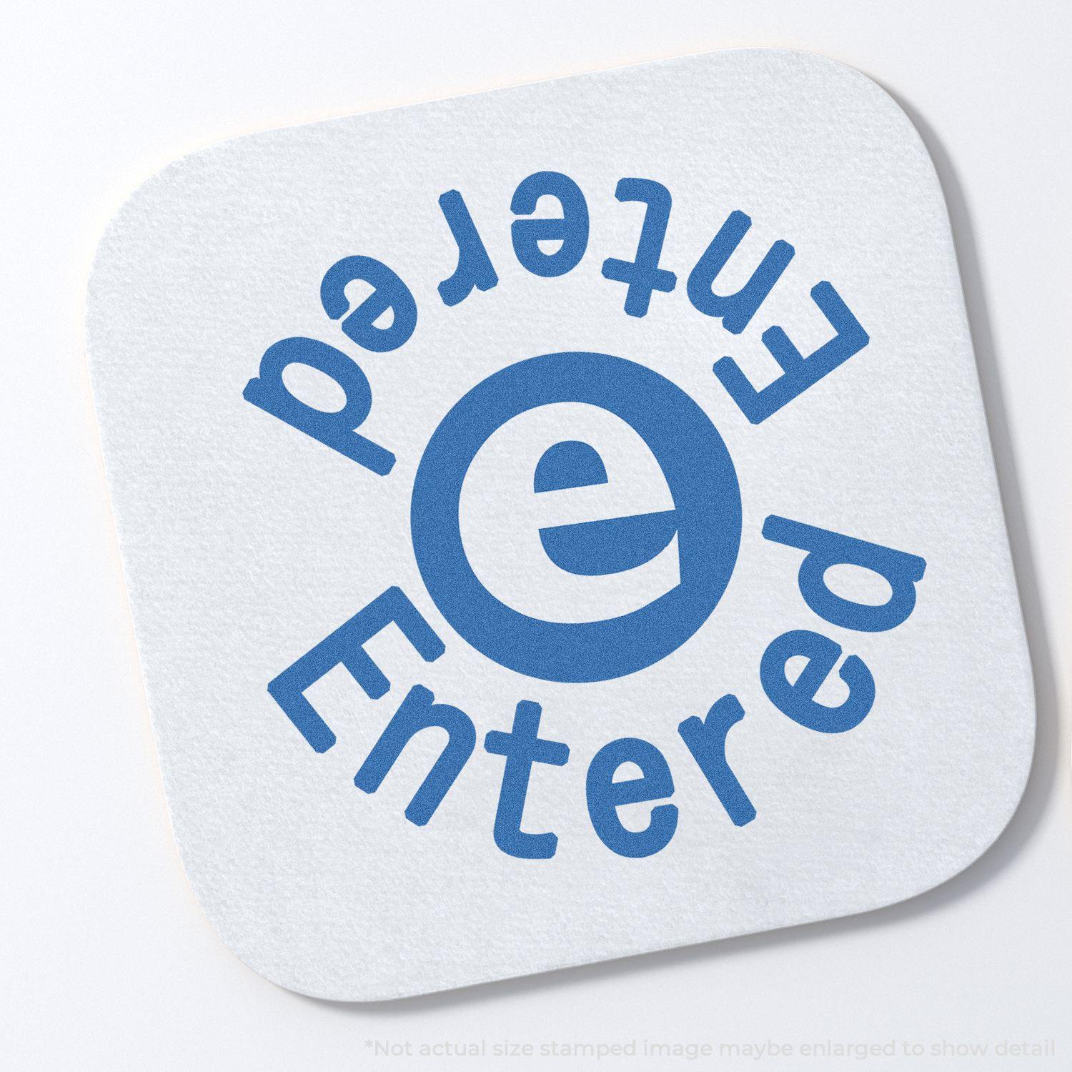 Round Blue Entered Xstamper Stamp imprint on white paper, showing the word Entered in blue text around a central e symbol.