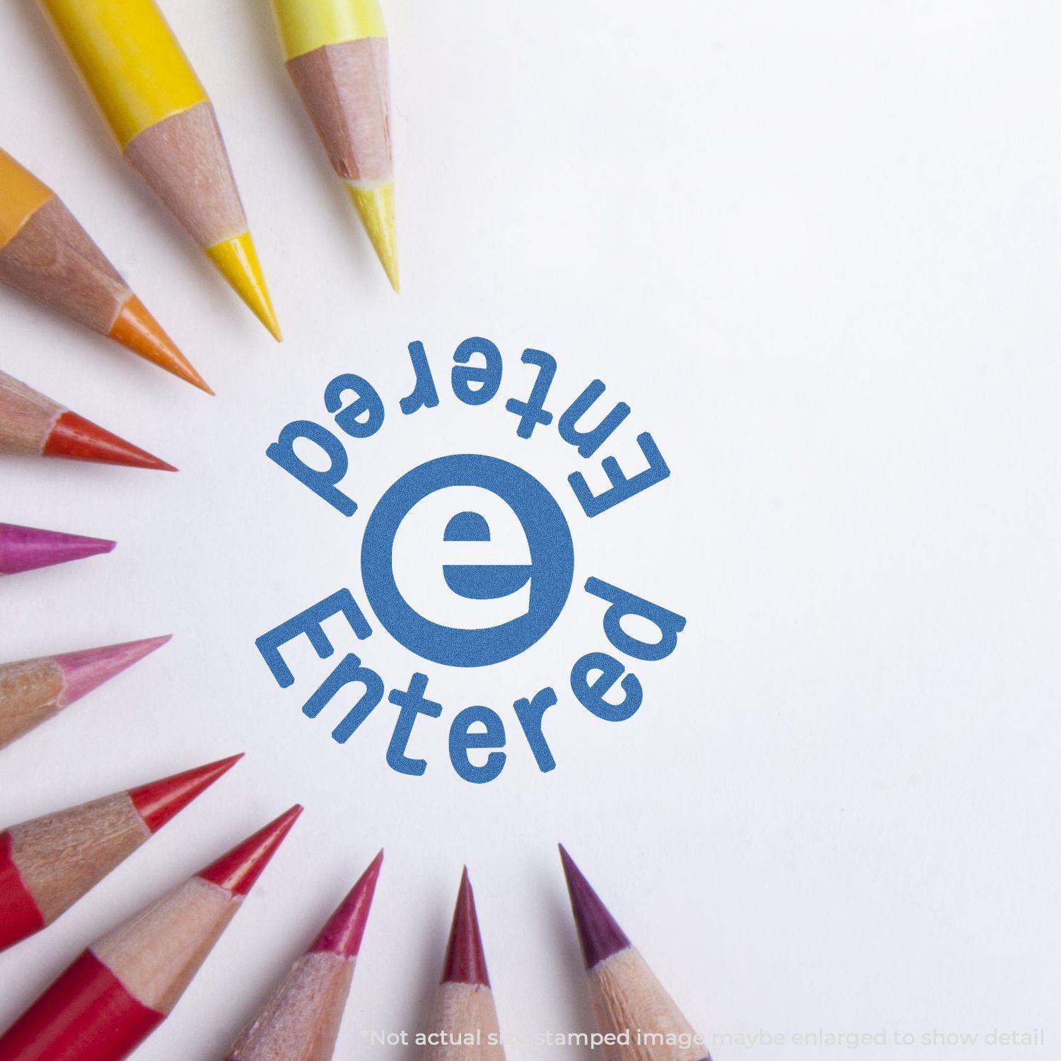 Round Blue Entered Xstamper Stamp impression on white paper, surrounded by colorful pencils arranged in a circle.