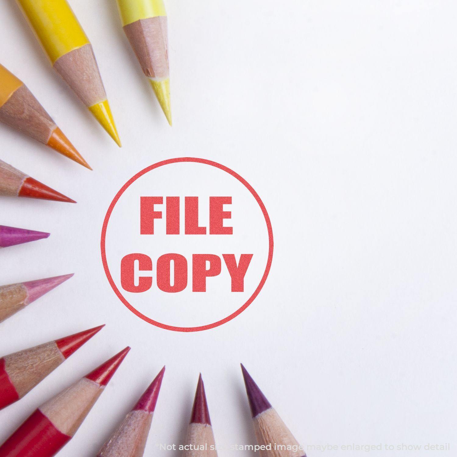Round File Copy Xstamper Stamp impression in red ink on white paper, surrounded by colored pencils arranged in a circular pattern.
