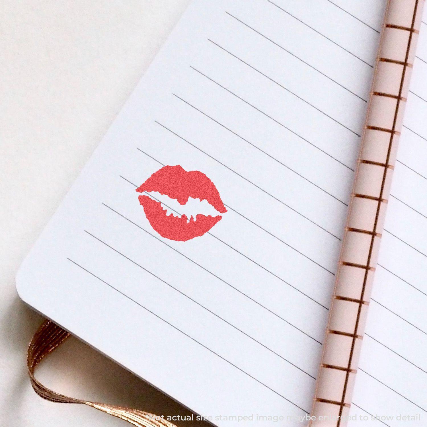 Round Kiss Xstamper Stamp imprint of red lips on a lined notebook page with a copper spiral binding.