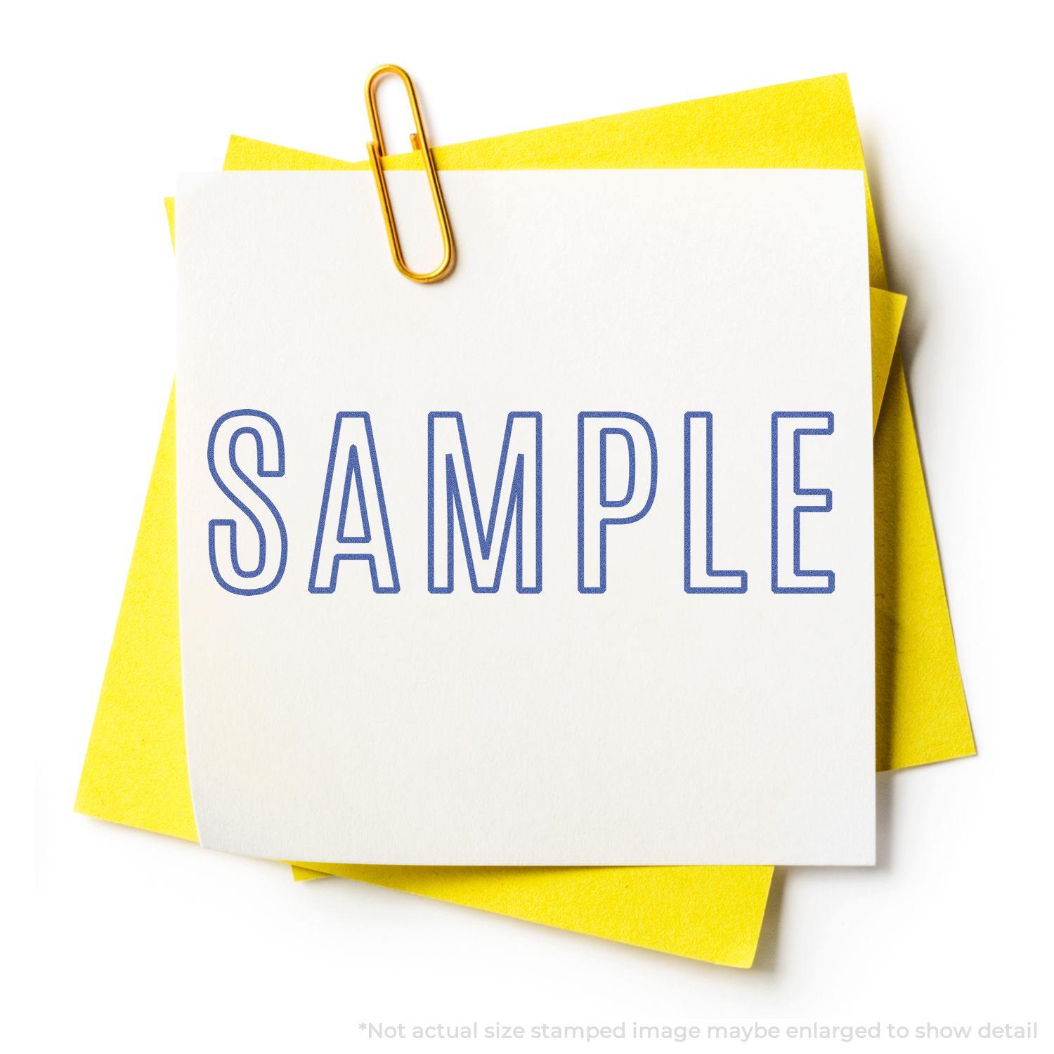 Sample Xstamper Stamp in use, stamping the word SAMPLE in blue ink on a white paper clipped to yellow sheets.
