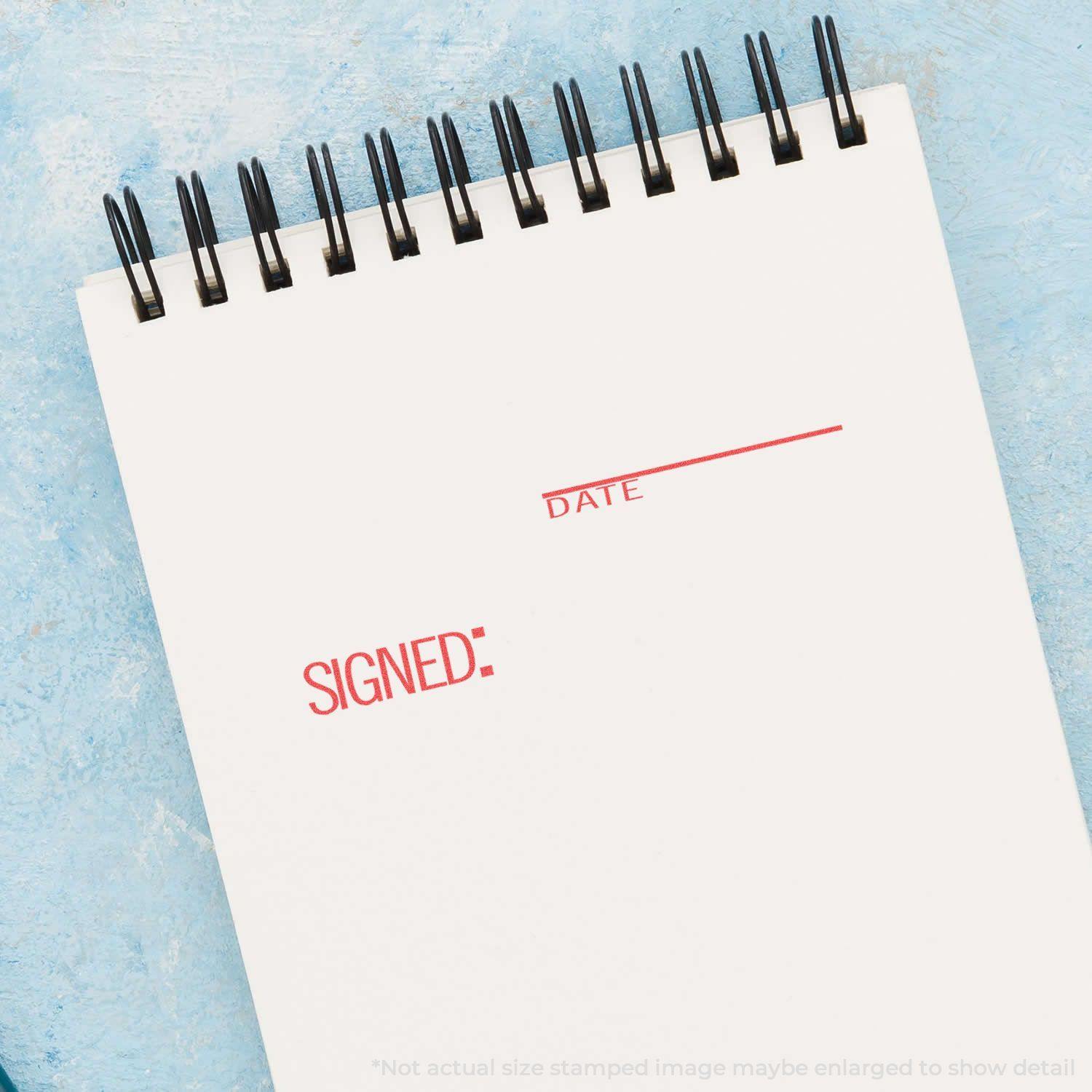 A notebook with SIGNED: and DATE stamped in red using the Signed: Date Xstamper Stamp on a blue textured background.