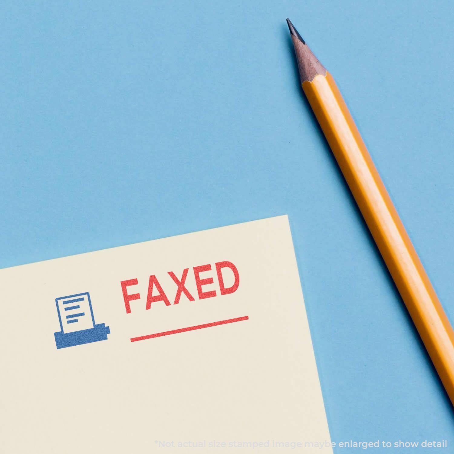Two-Color Faxed Xstamper Stamp in use, showing a red FAXED text and blue fax machine icon stamped on a paper next to a pencil.