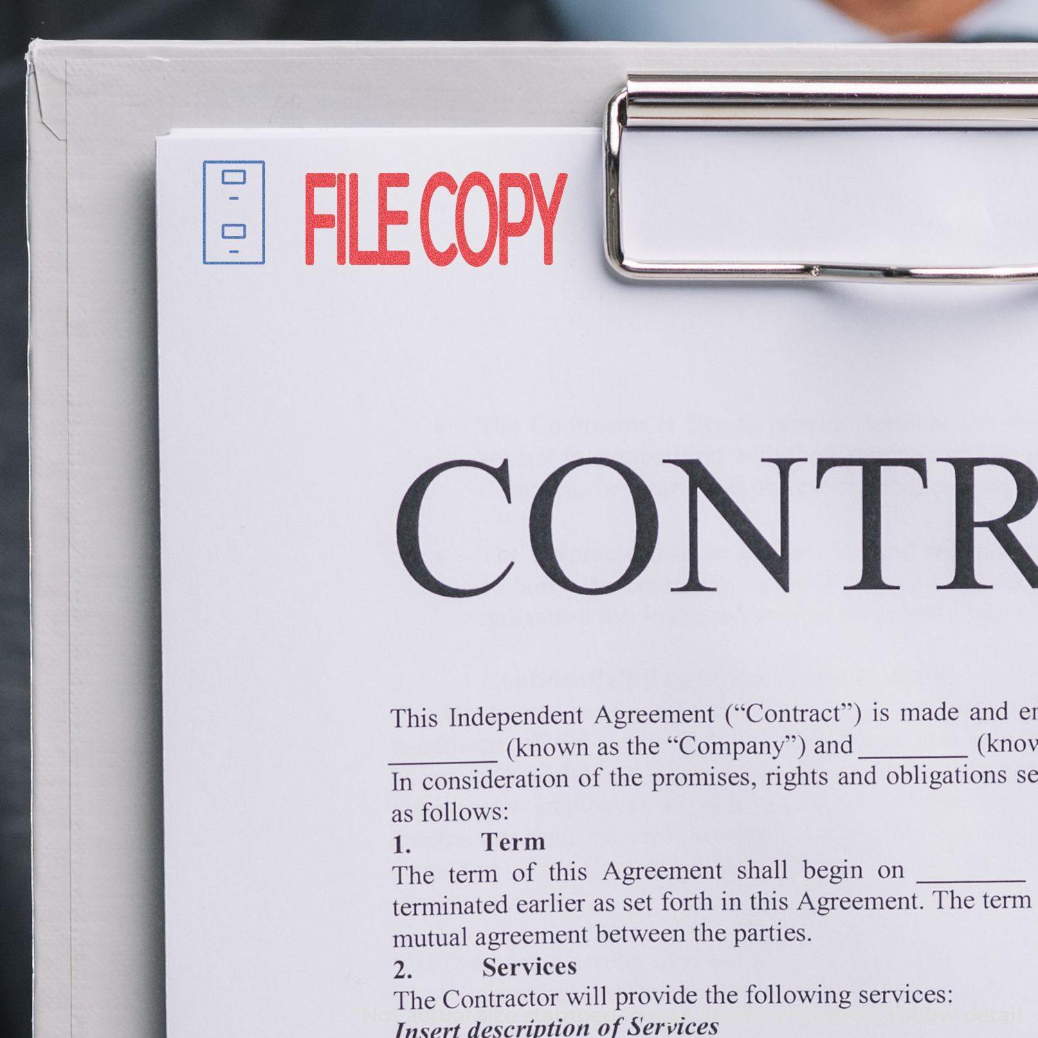 A clipboard with a contract stamped FILE COPY in red using the Two-Color File Copy Xstamper Stamp.