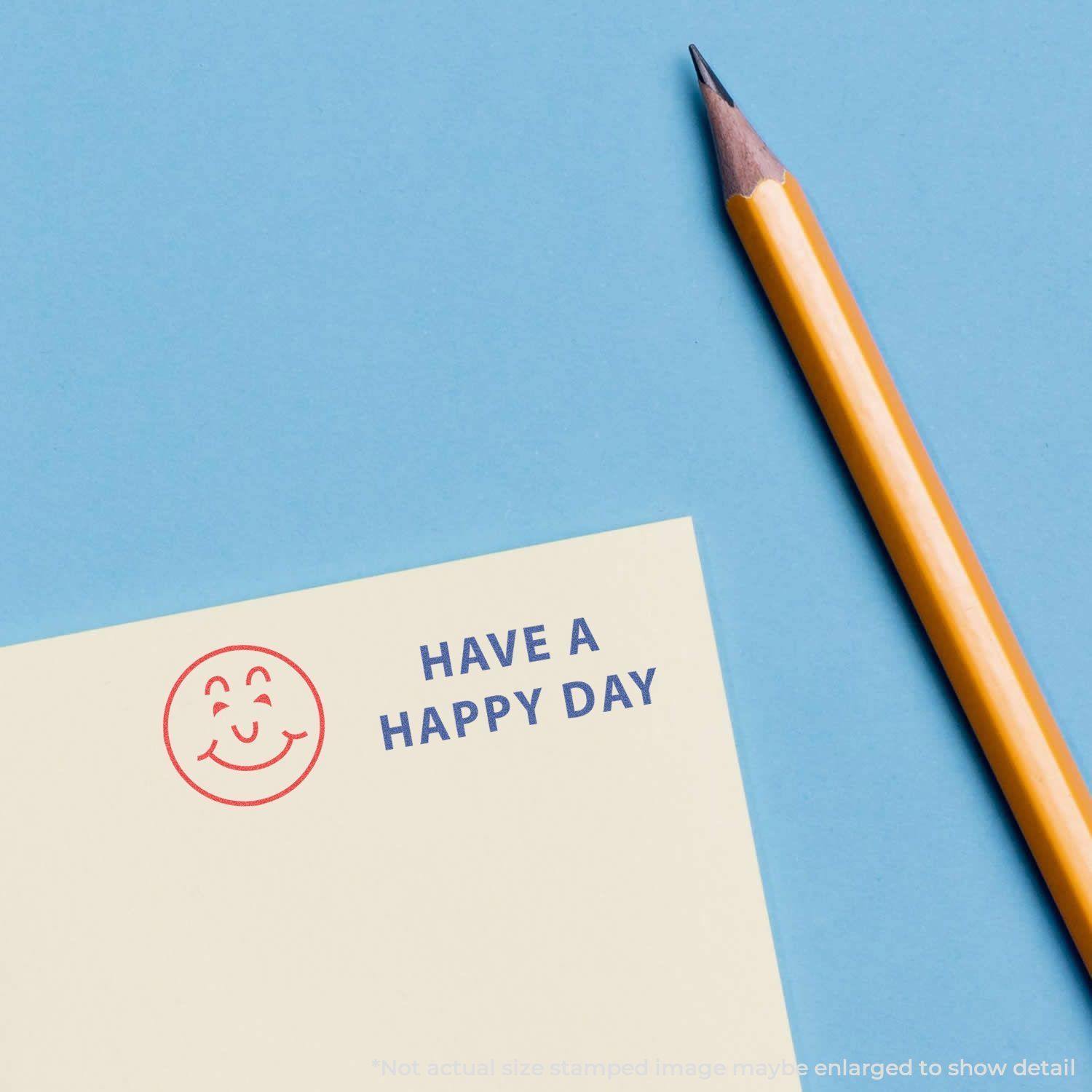 Two-Color Have A Happy Day Xstamper Stamp on paper with a smiley face and 'HAVE A HAPPY DAY' text, next to a yellow pencil on a blue background.