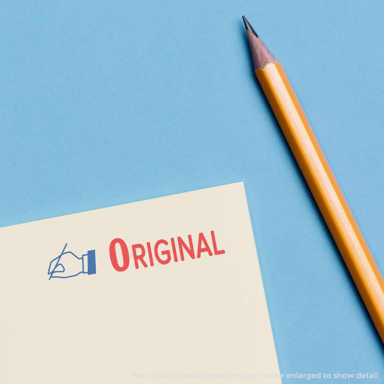 Two-Color Original Xstamper Stamp imprint on paper with a pencil beside it on a blue background.