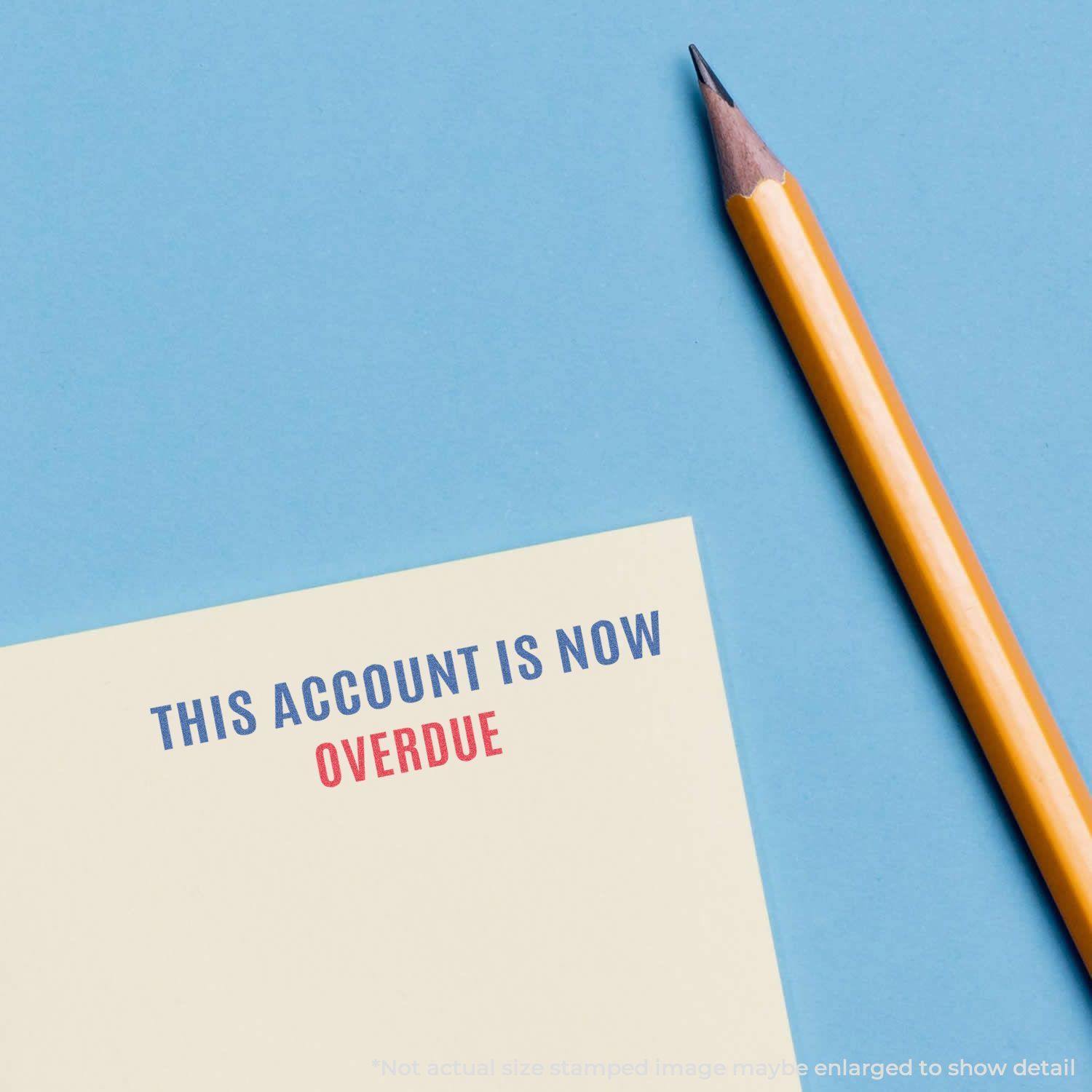 Two-Color This Account Is Now Overdue Xstamper Stamp on a paper with a pencil beside it on a blue background.