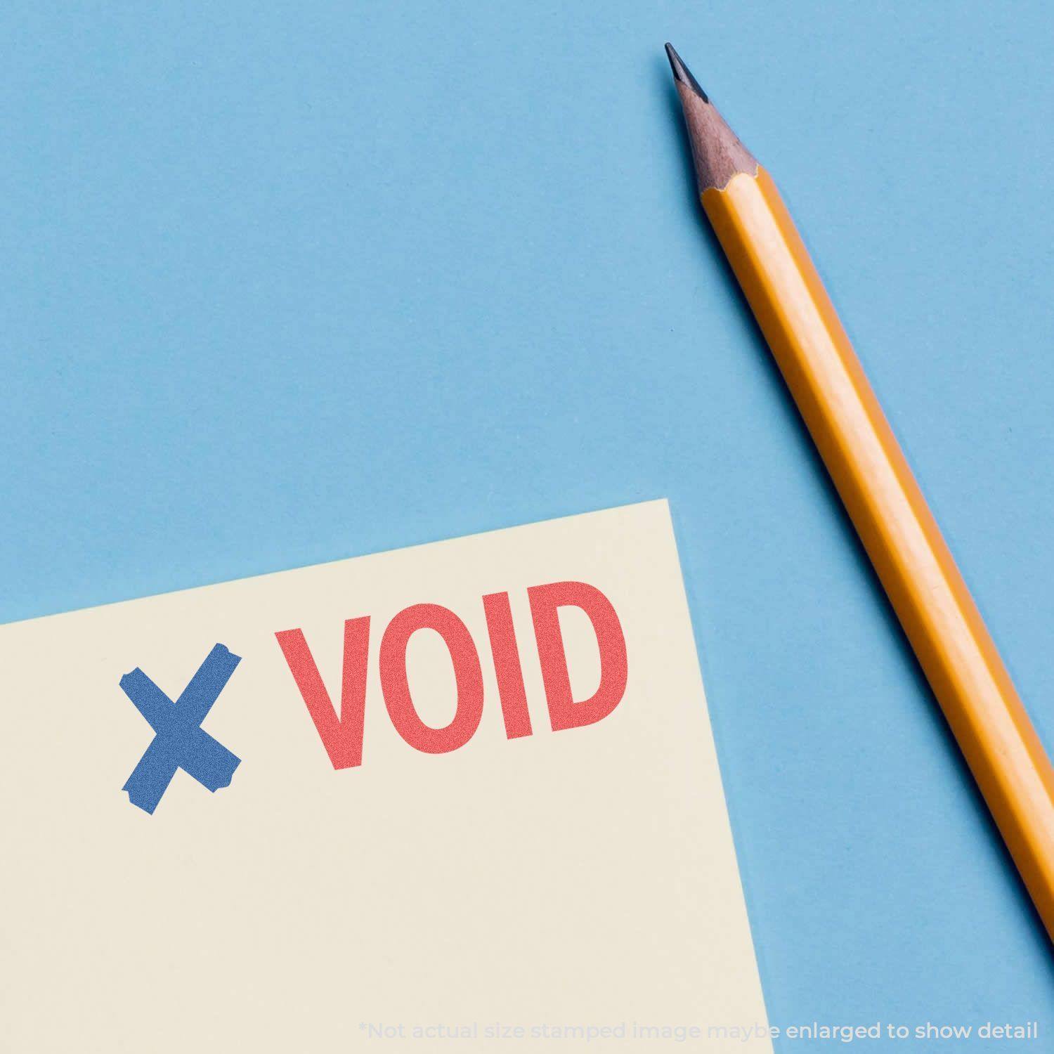 Two-Color Void Xstamper Stamp imprint on paper with a blue X and red VOID next to a yellow pencil on a blue background.