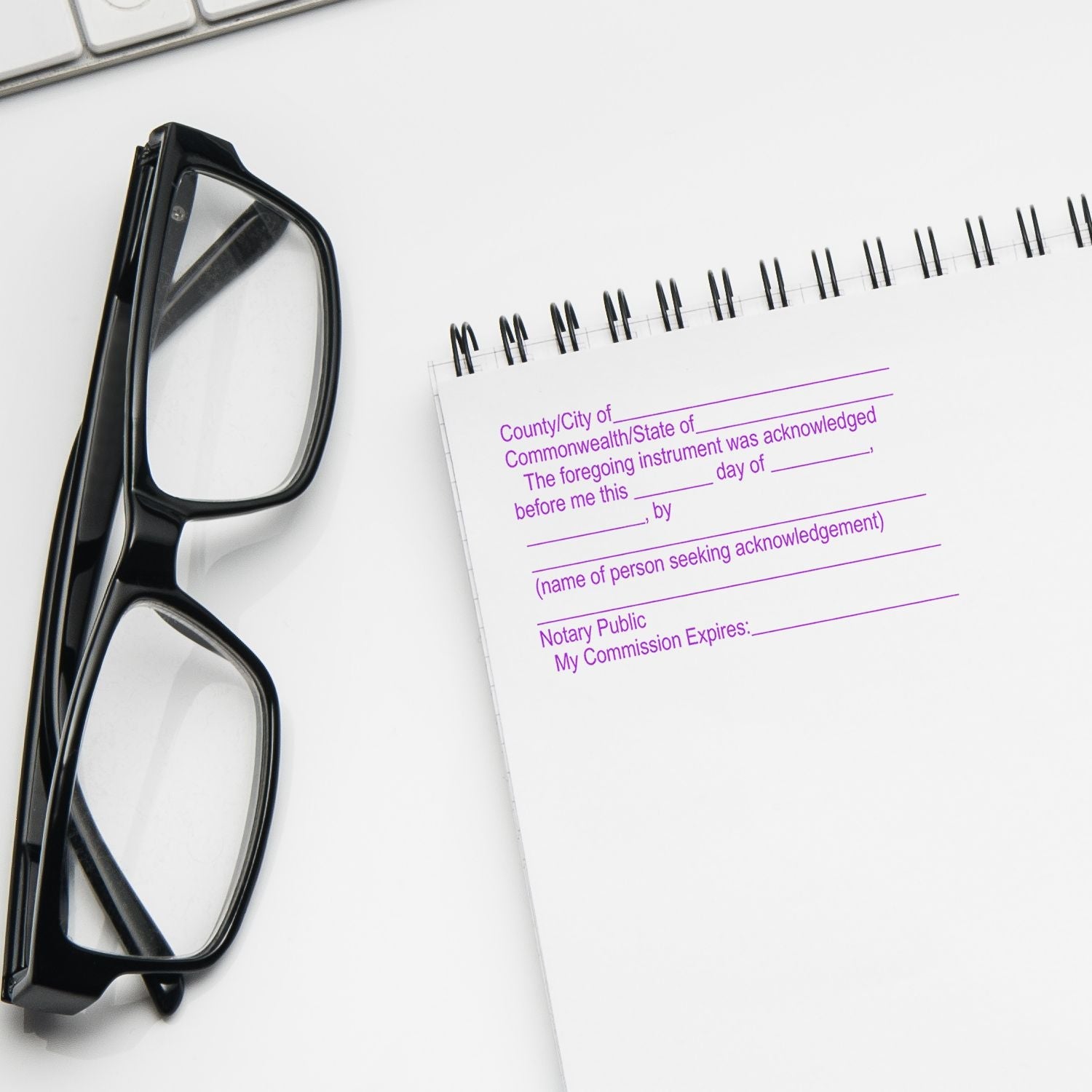 Notary Supplies Feature Image: Glasses and a notary acknowledgment form on a spiral notebook, ready for use.