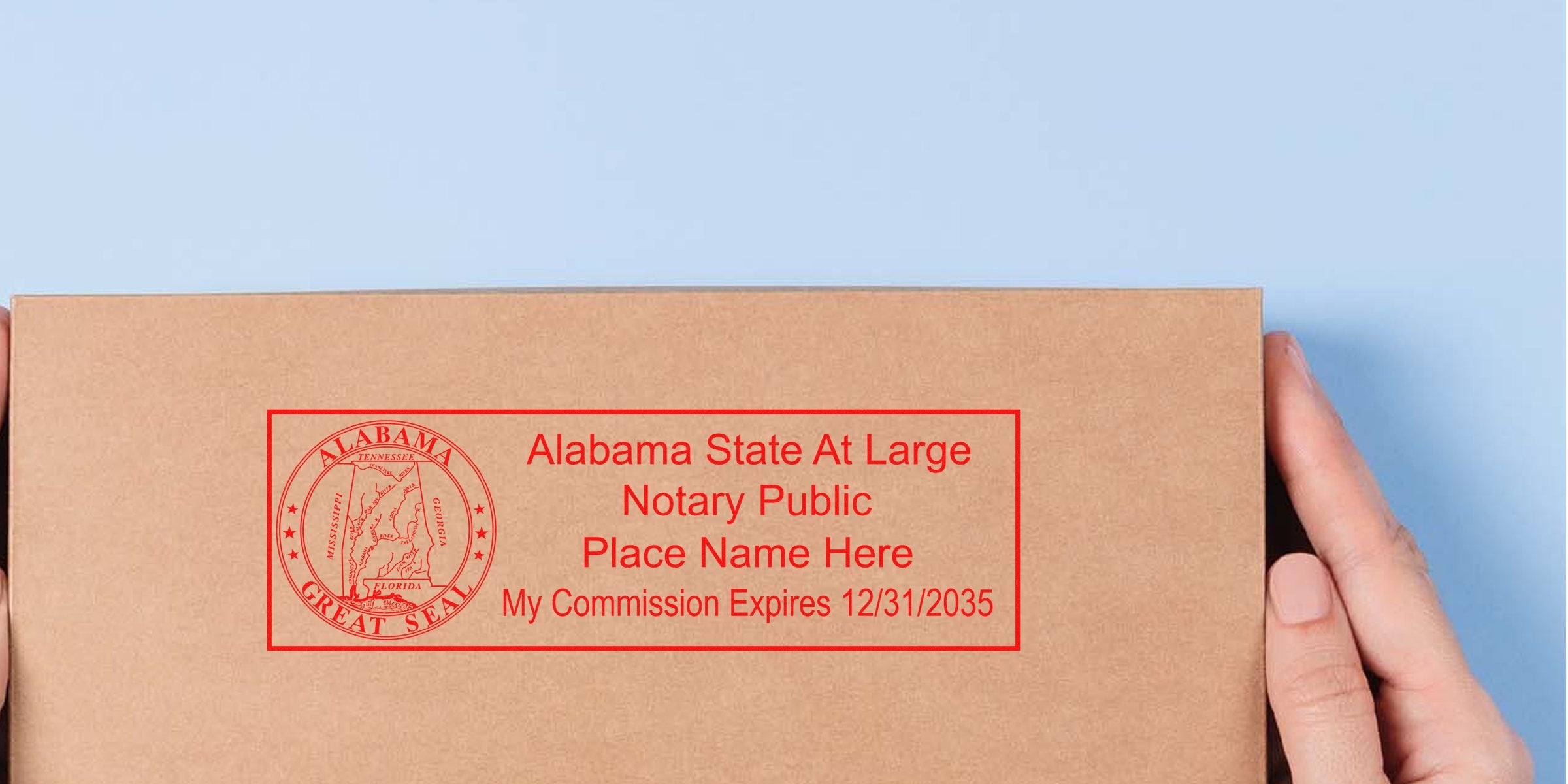 Close-up of hands holding a cardboard envelope stamped with a red Alabama State At Large notary public seal and expiration date, showing official notary stamp and seal on brown package against a pale blue background