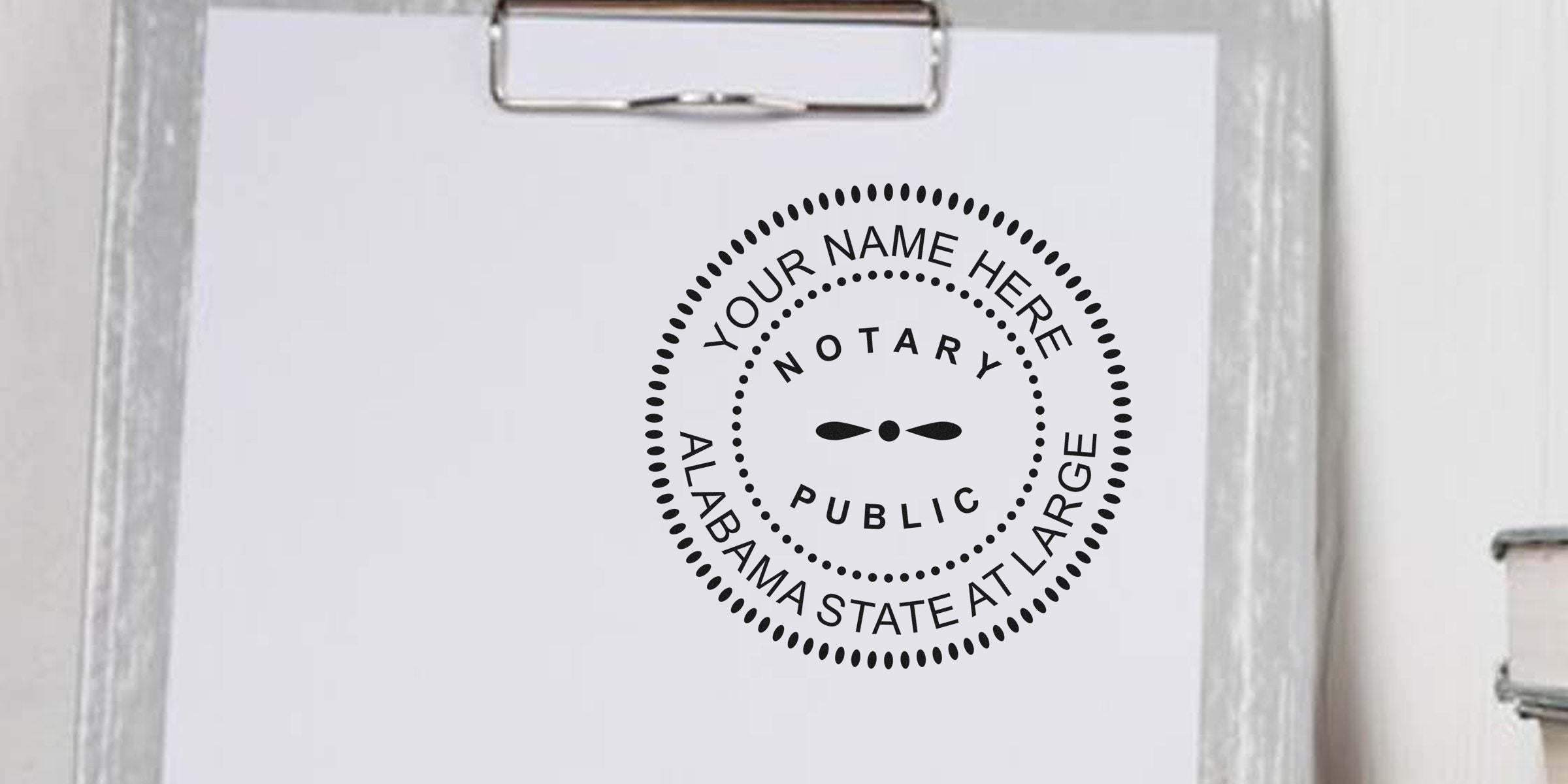 Customizable notary public stamp mockup reading "Your Name Here, Notary Public, Alabama State At Large" printed on white paper on a clipboard — placeholder design for Alabama notary seal